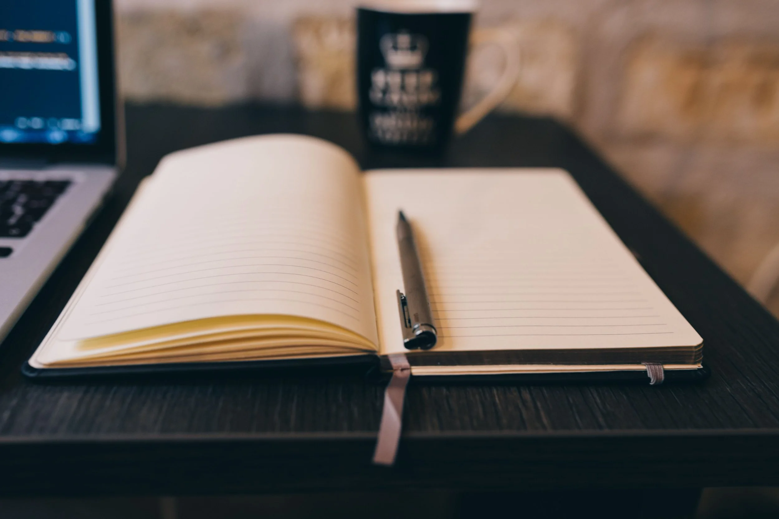 An open planning diary on a desk with blank pages and a pen.