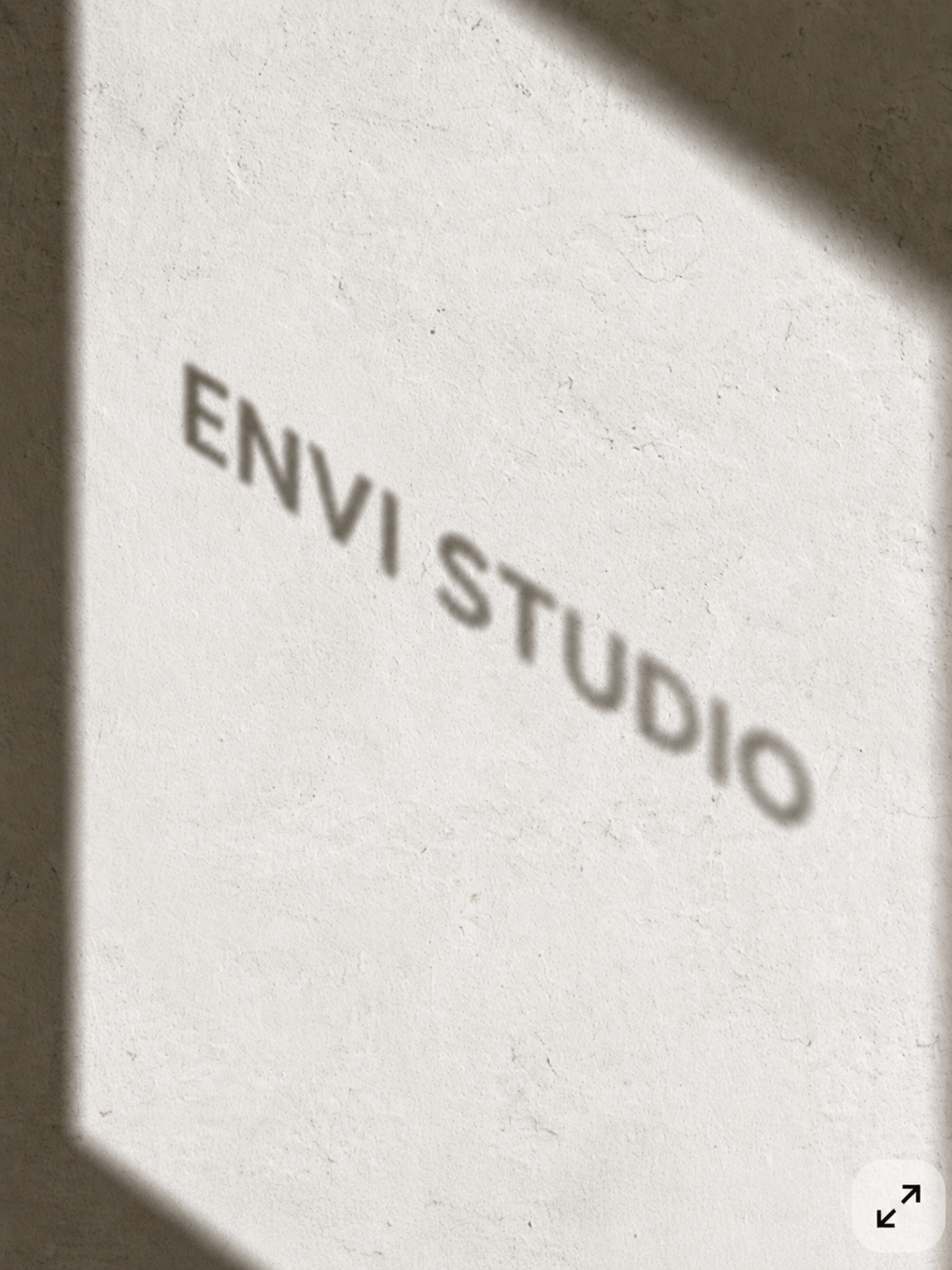 Shadow of the word 'ENVI STUDIOS' cast on a plain wall.