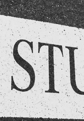 Close-up of part of a white street or traffic sign with the letters 'STU' visible.