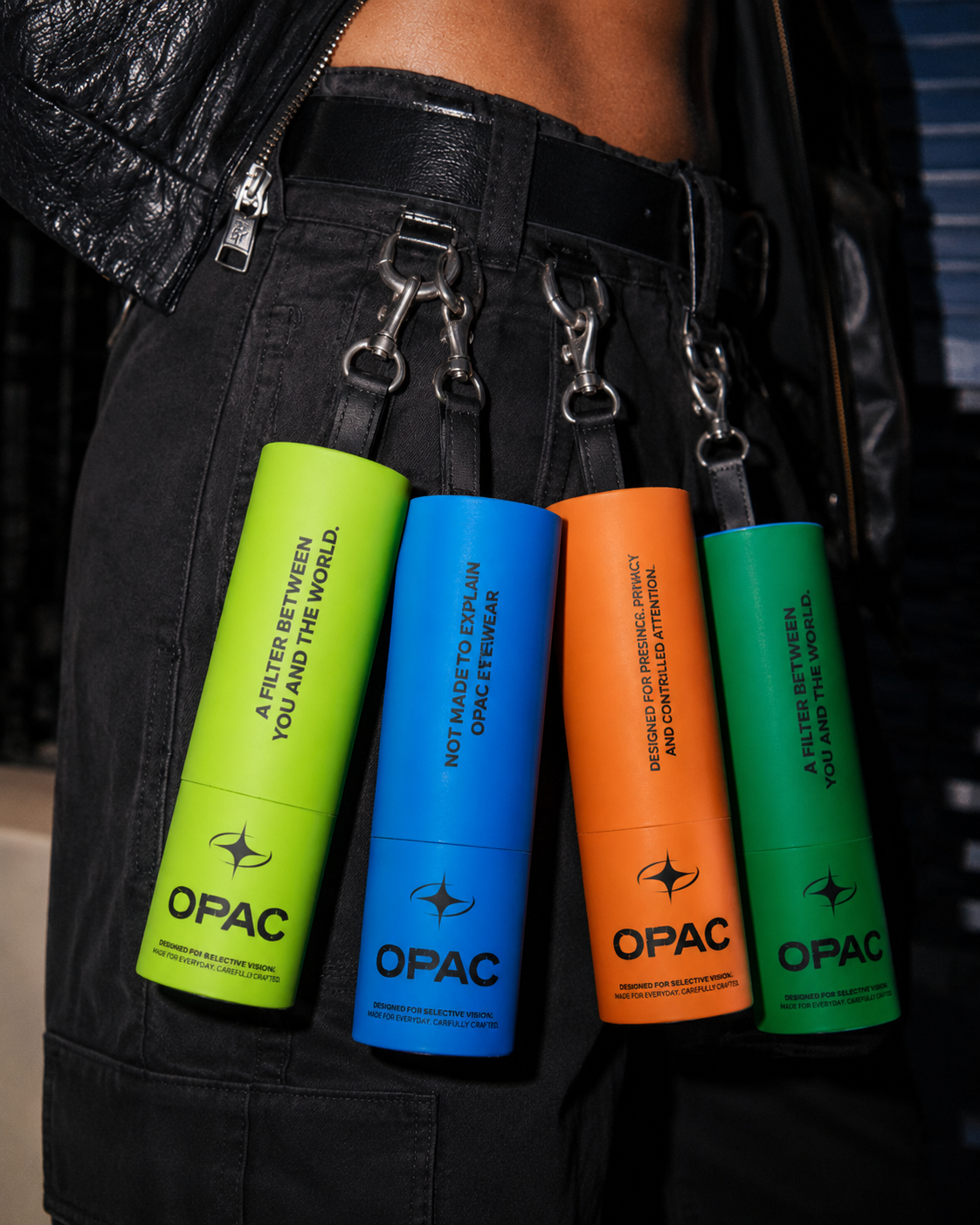 Colourful OPAC glasses cases clipped to a belt on black jeans and a leather jacket