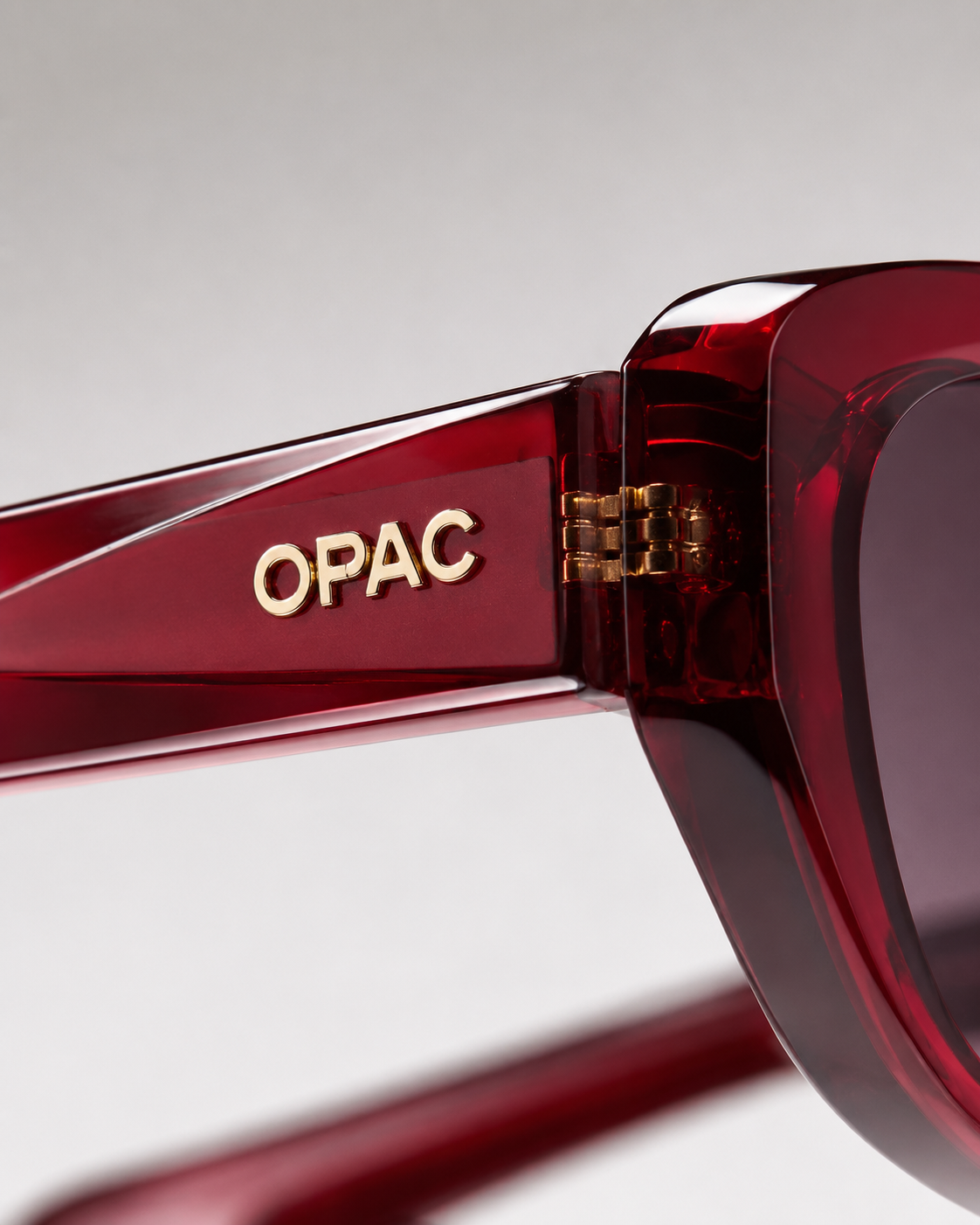 Detail of glossy red OPAC sunglasses with the gold logo on the temple