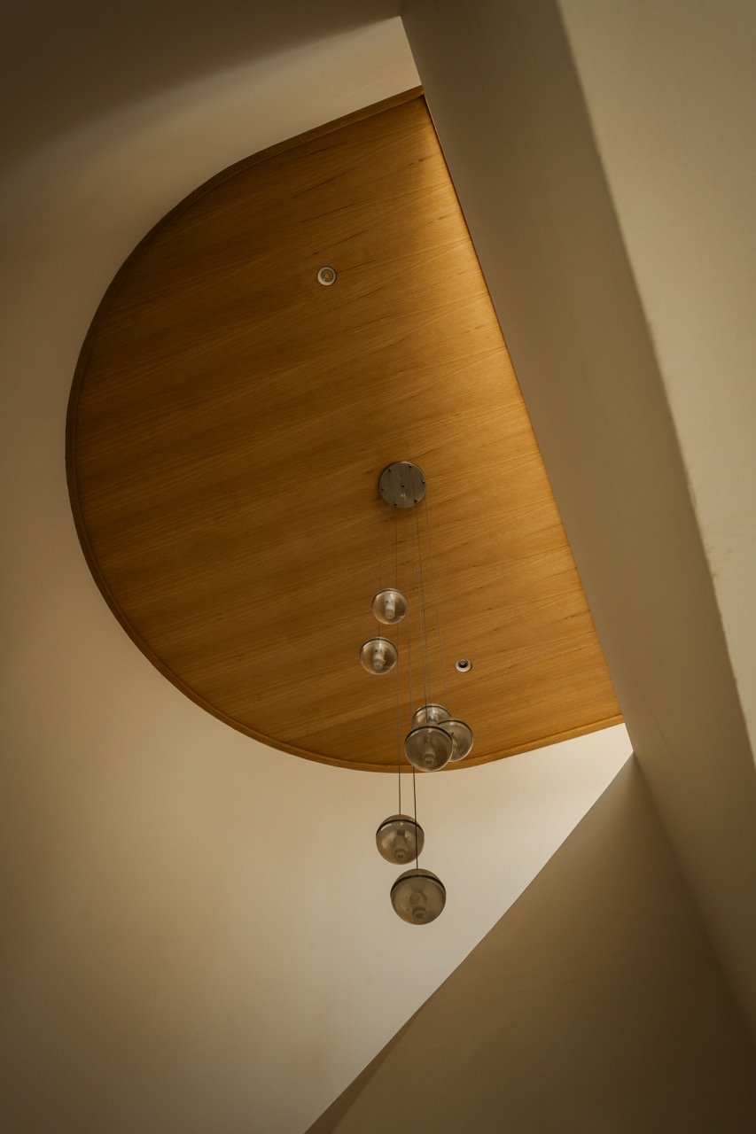Ceiling with a wooden oval panel and multiple hanging pendant lights.