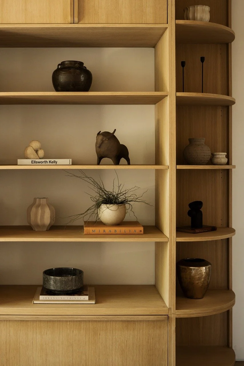 Wooden shelving unit with decorative vases, sculptures, and books.