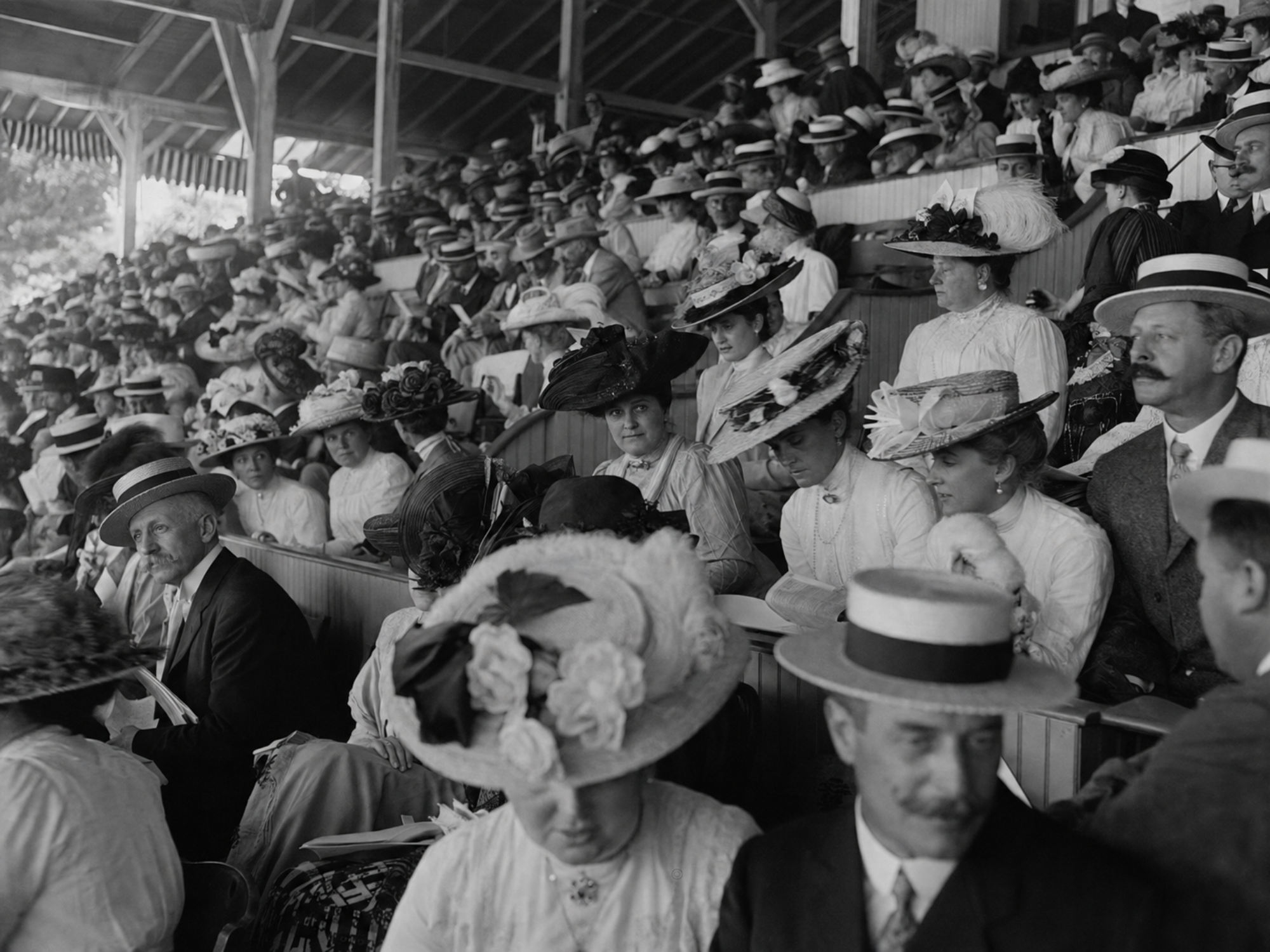 Crowded Saratoga Race Course grandstand filled with elaborate hats and straw boaters around 1910.