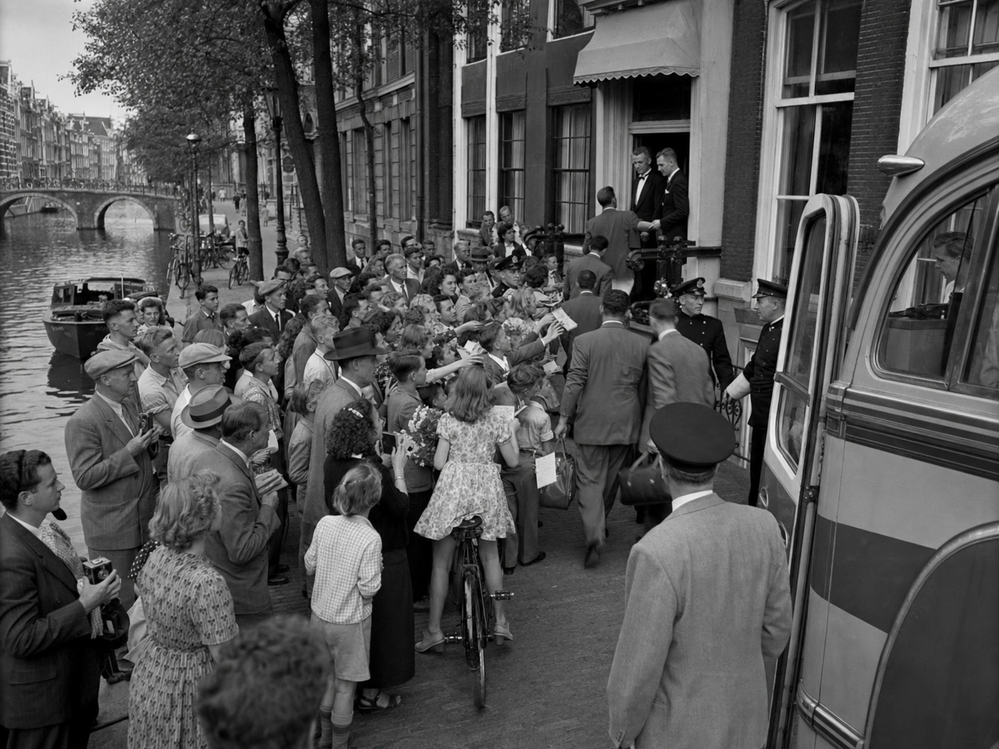 Black-and-white photograph of supporters gathered outside the Albany delegation’s Rotterdam hotel, with the team bus at the curb.