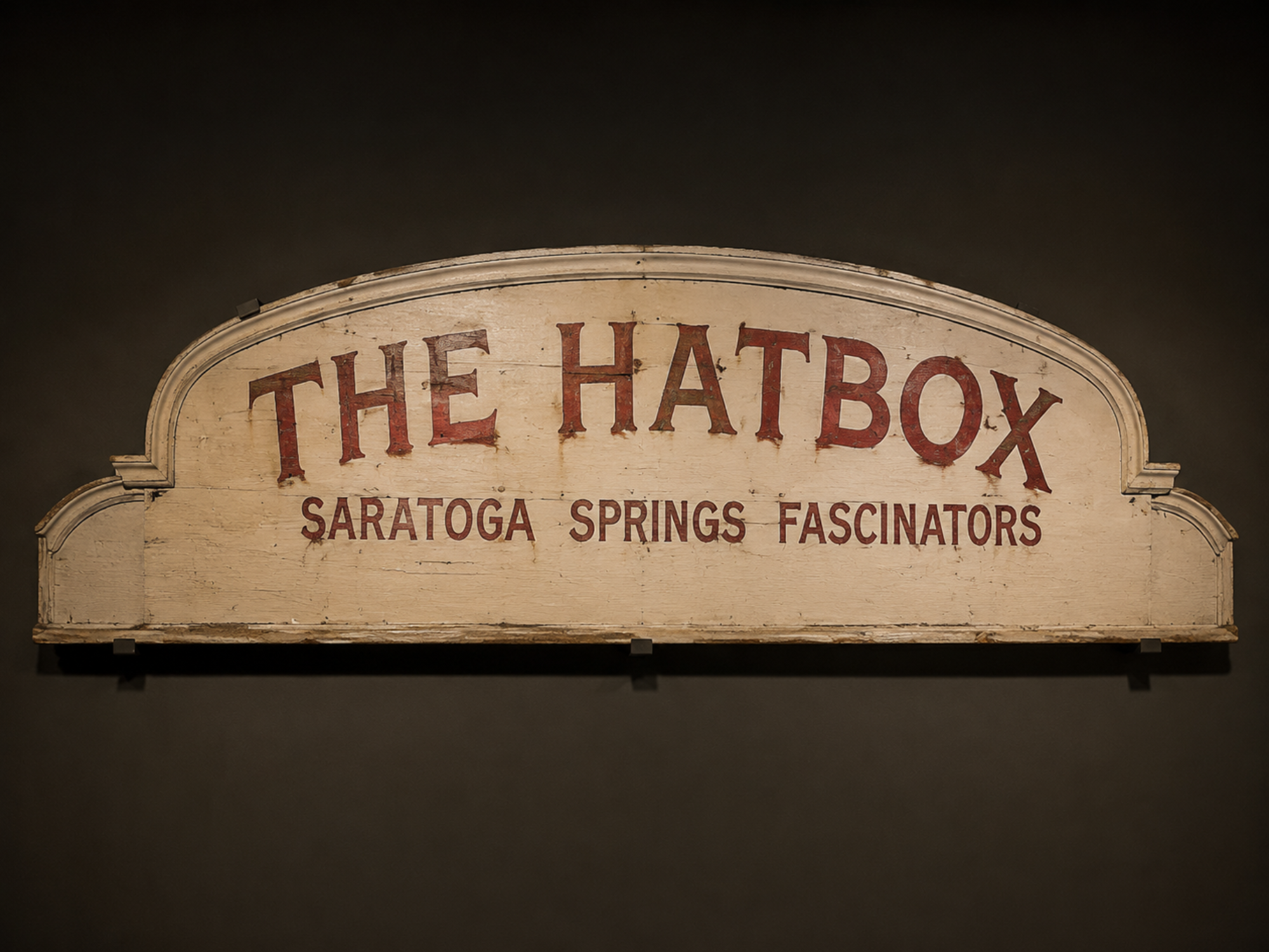 The preserved wooden entrance sign from The Hatbox is mounted on a museum wall.