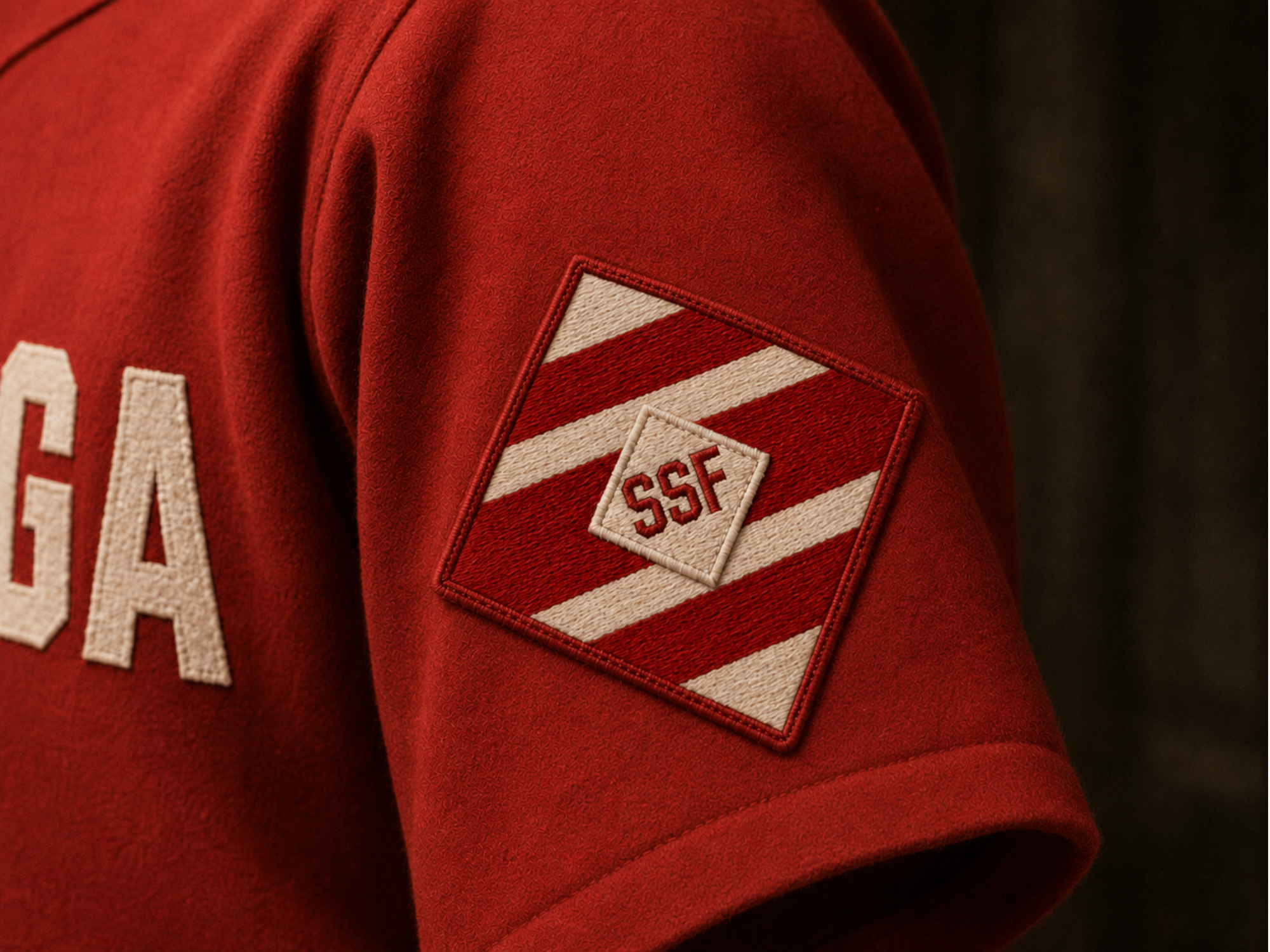A preserved red-and-white SSF racing-silk diamond patch displayed on the sleeve of a Red squad uniform.