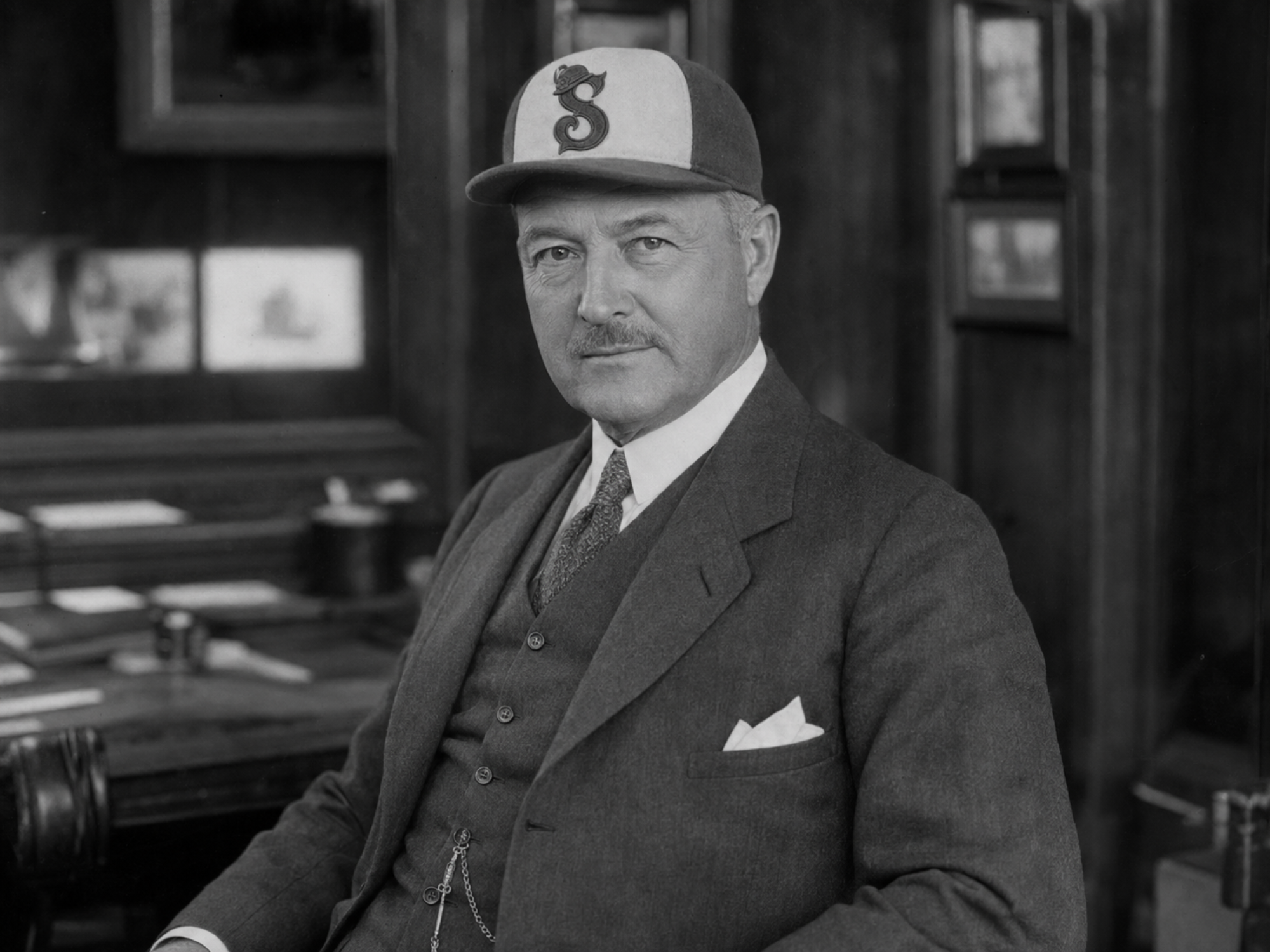 Jules Devereux, founder and president of the Saratoga Springs Fascinators, poses in a suit and the club’s four-panel cap.