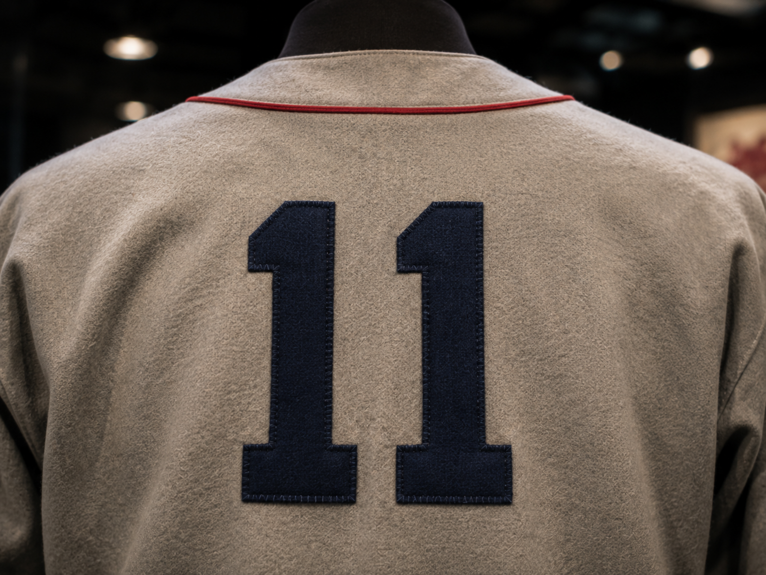 Close-up of the back of a gray Davenport Deadheaders travel jersey with red collar piping and a navy number 11.