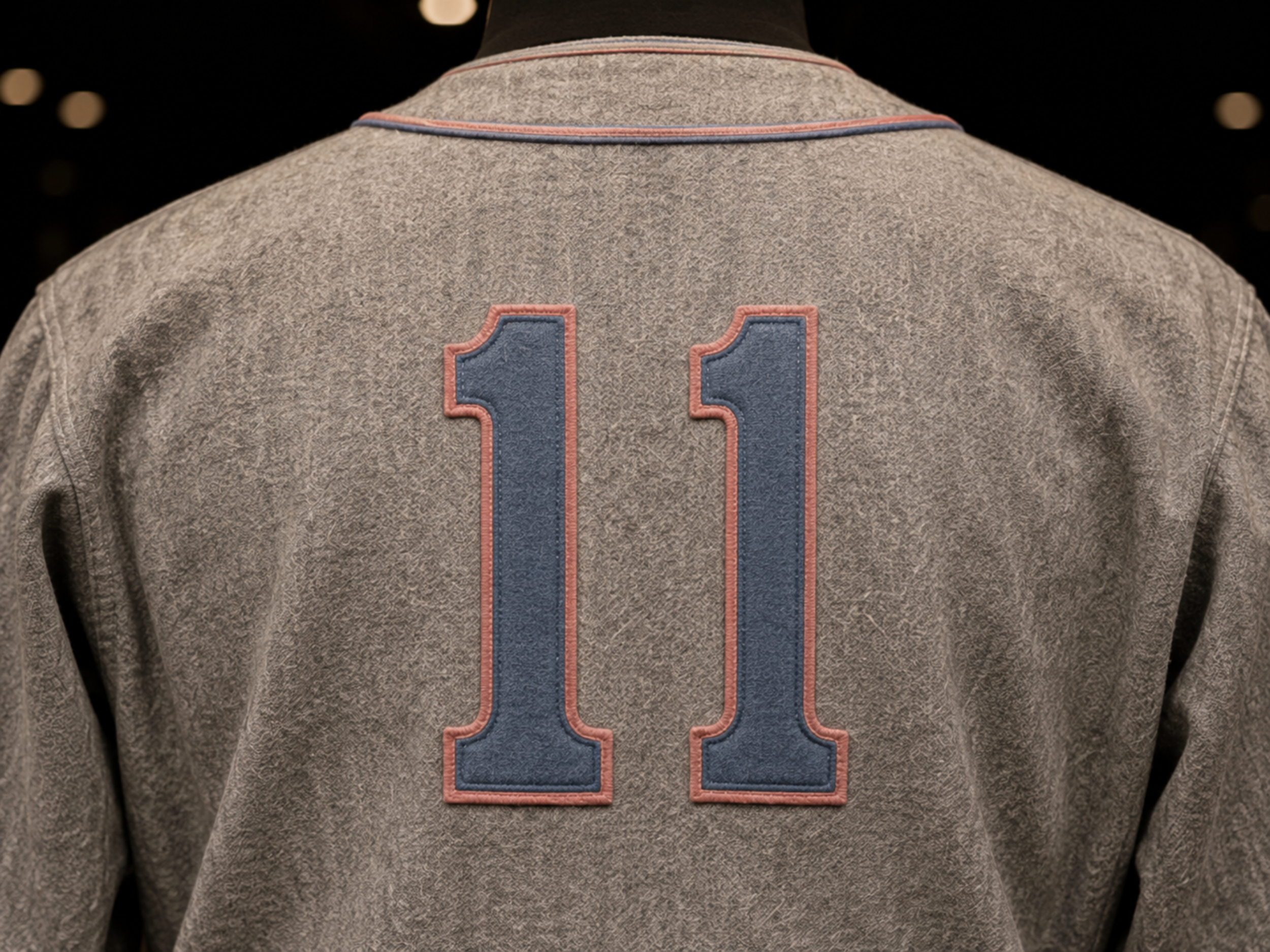 Close-up of powder-blue number 11 edged in rose pink on the gray Tyler Roses travel jersey.