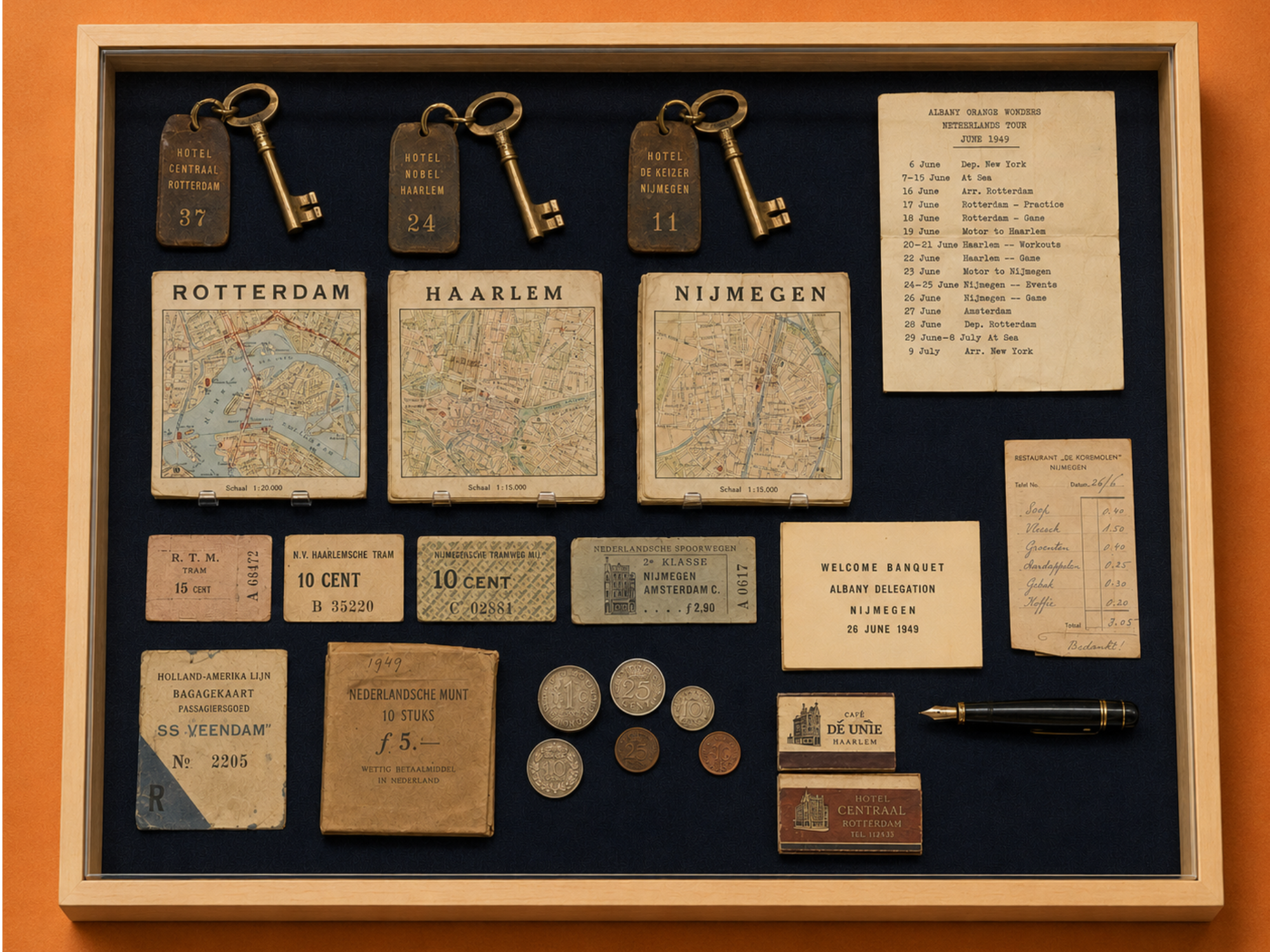 A blonde-wood museum vitrine containing three brass hotel keys, maps of Rotterdam, Haarlem and Nijmegen, a 1949 tour itinerary, tickets, a banquet invitation, receipts, Dutch coins, matchbooks and a fountain pen on dark navy fabric.