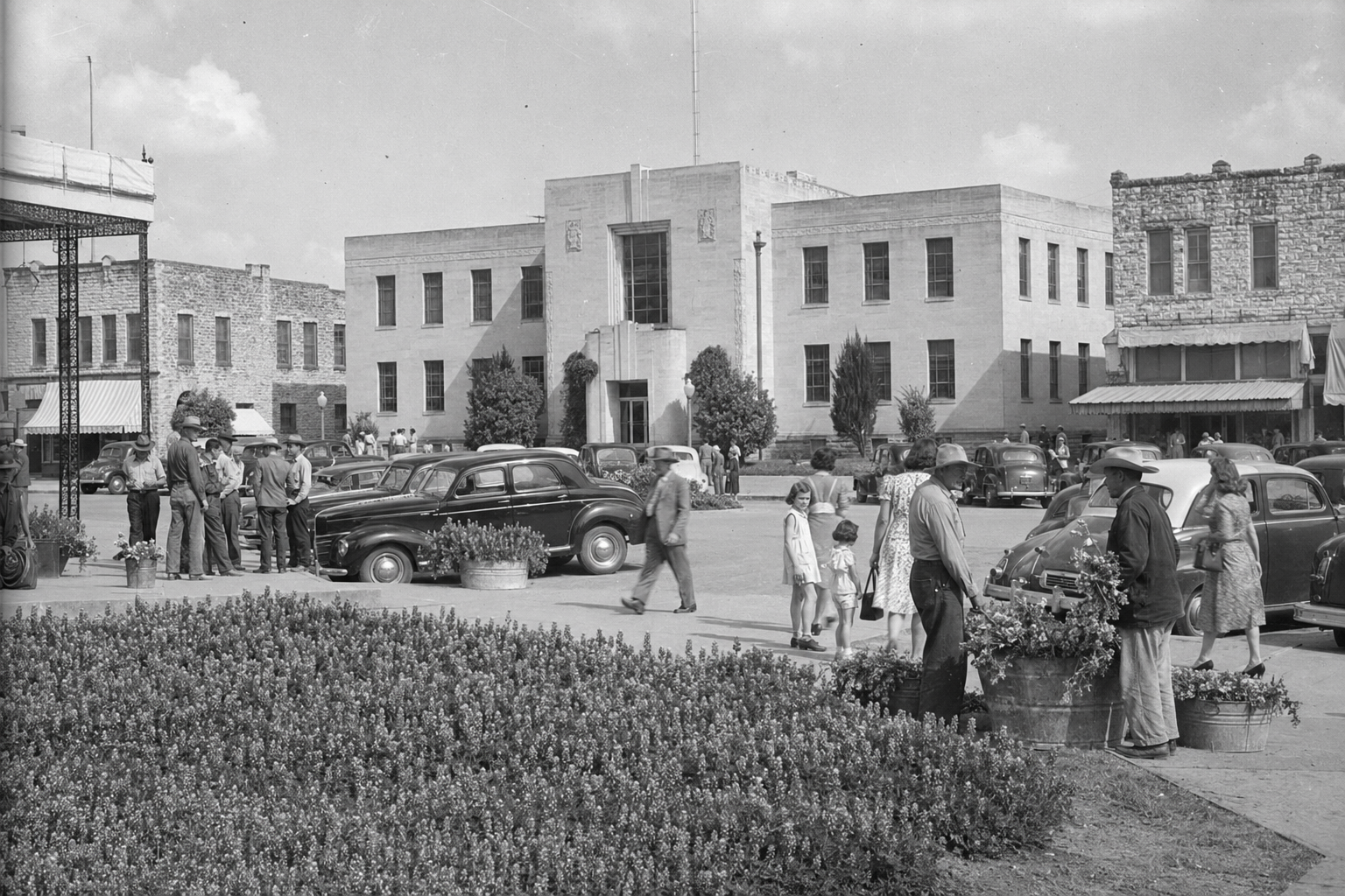 Late-1940s Burnet courthouse square filled with townspeople, period automobiles and bluebonnets.