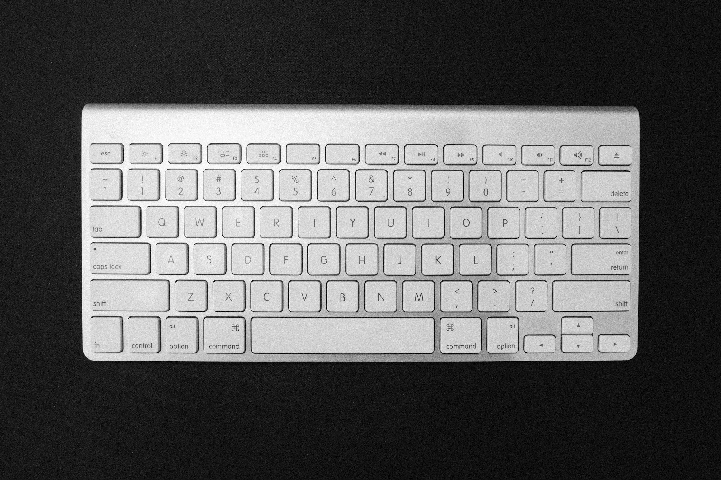 A white wireless keyboard on a black surface.