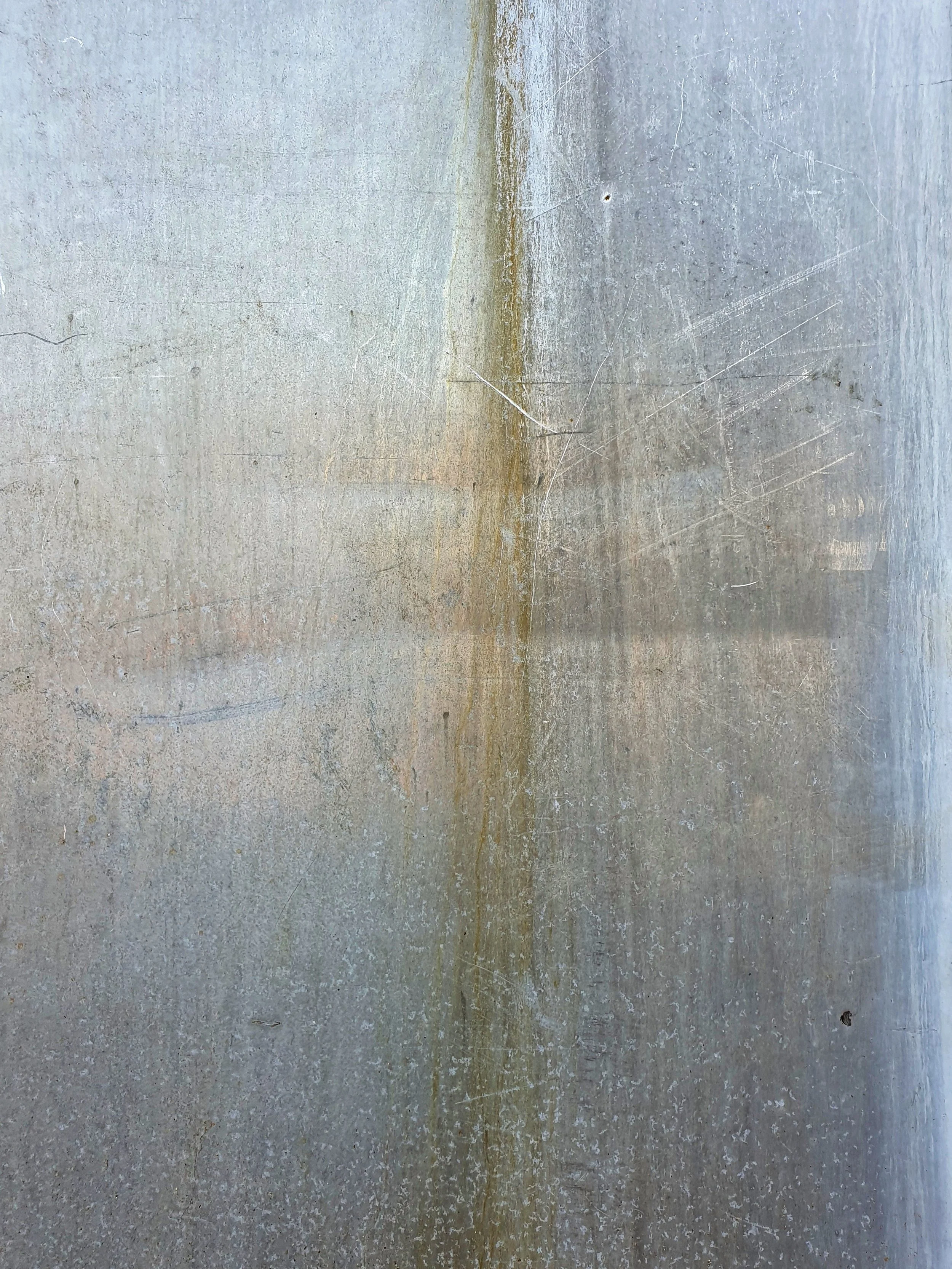 Close-up of a worn, scratched, and stained concrete or metal surface.