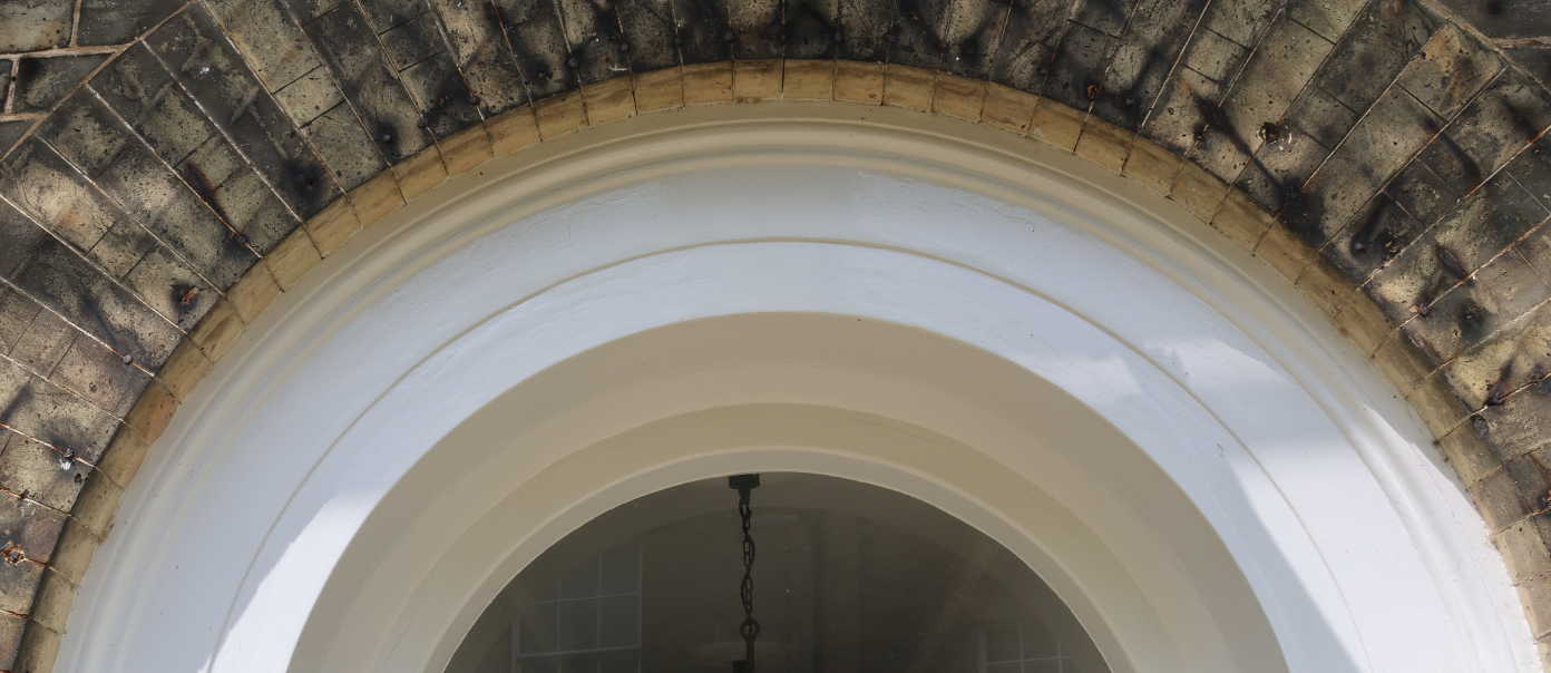 Close-up view of a brick arch doorway with white molding and a hanging chain from the ceiling.