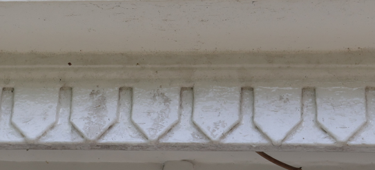 Close-up of a white, weathered wooden surface with a decorative edge.