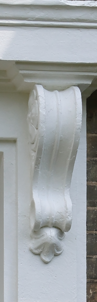 Close-up of decorative architectural corbel with ornate detailing, painted white.