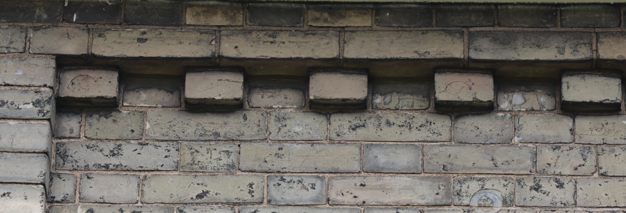Close-up of a brick wall with decorative brickwork at the top.