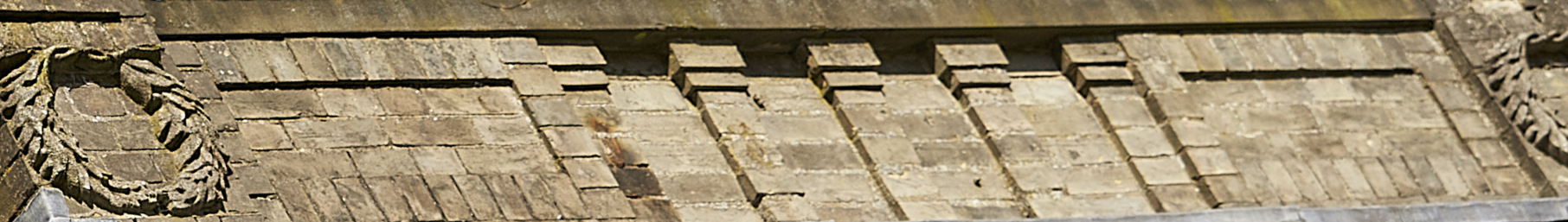 Close-up of an old brick building rooftop with decorative stone embellishments.