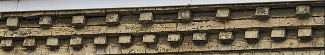 Close-up of a section of an ornate brick or stone building facade with detailed decorative patterns.