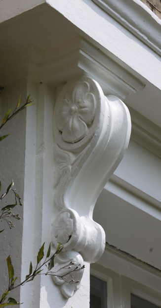 Close-up of an ornate white architectural corbel with a duck face design on the exterior of a building.