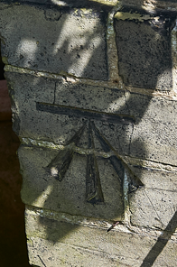 A graffiti or stencil art of an arrow pointing downwards on a brick wall.