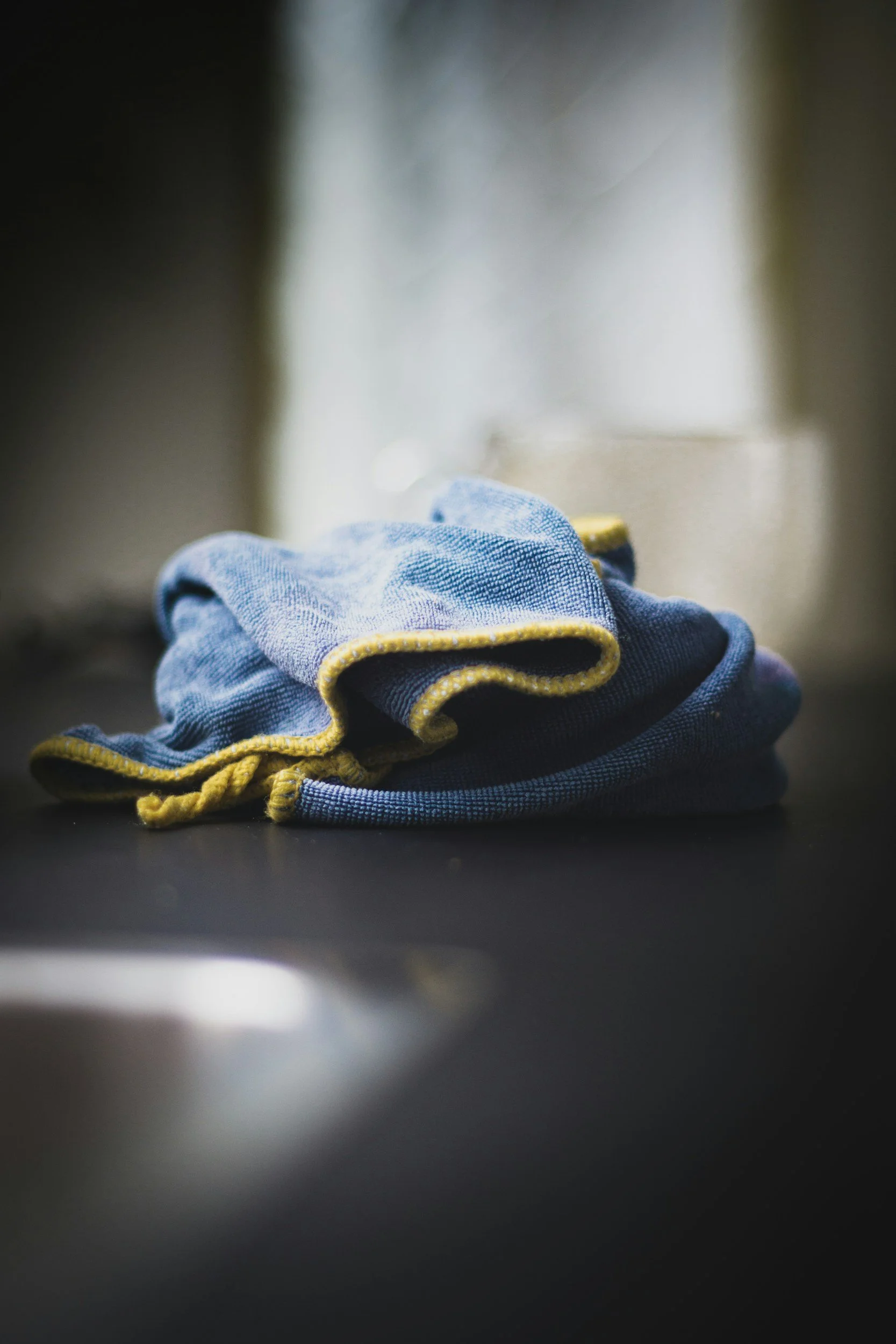 A pair of blue denim jeans with yellow stitching, folded and placed on a black surface.