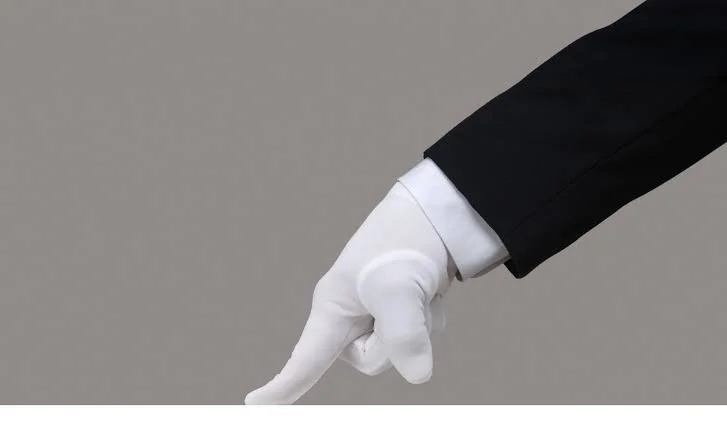 Person in black suit and white glove pointing downward with their index finger.