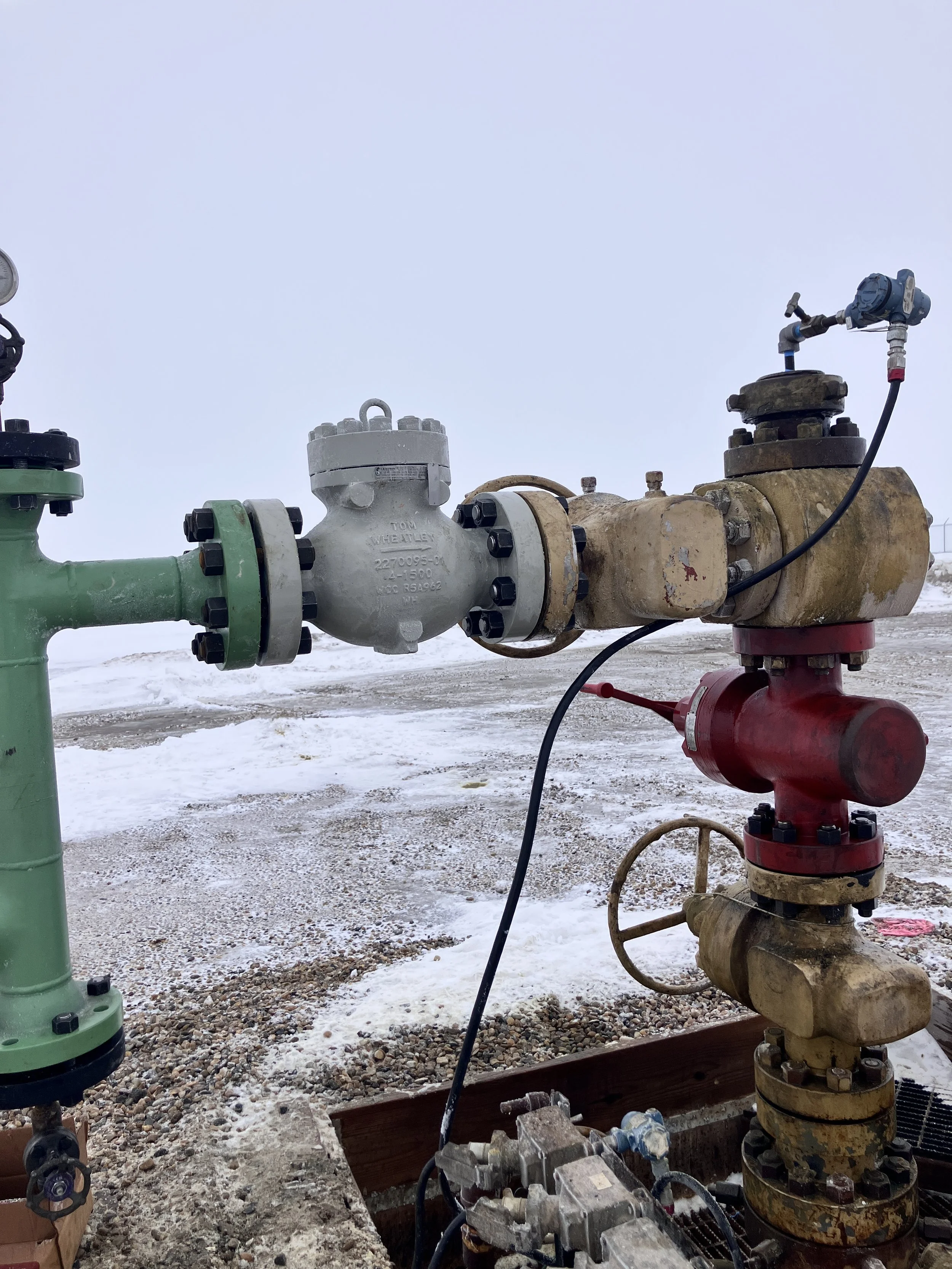 Industrial valve and pipe system outdoors with snow on the ground.