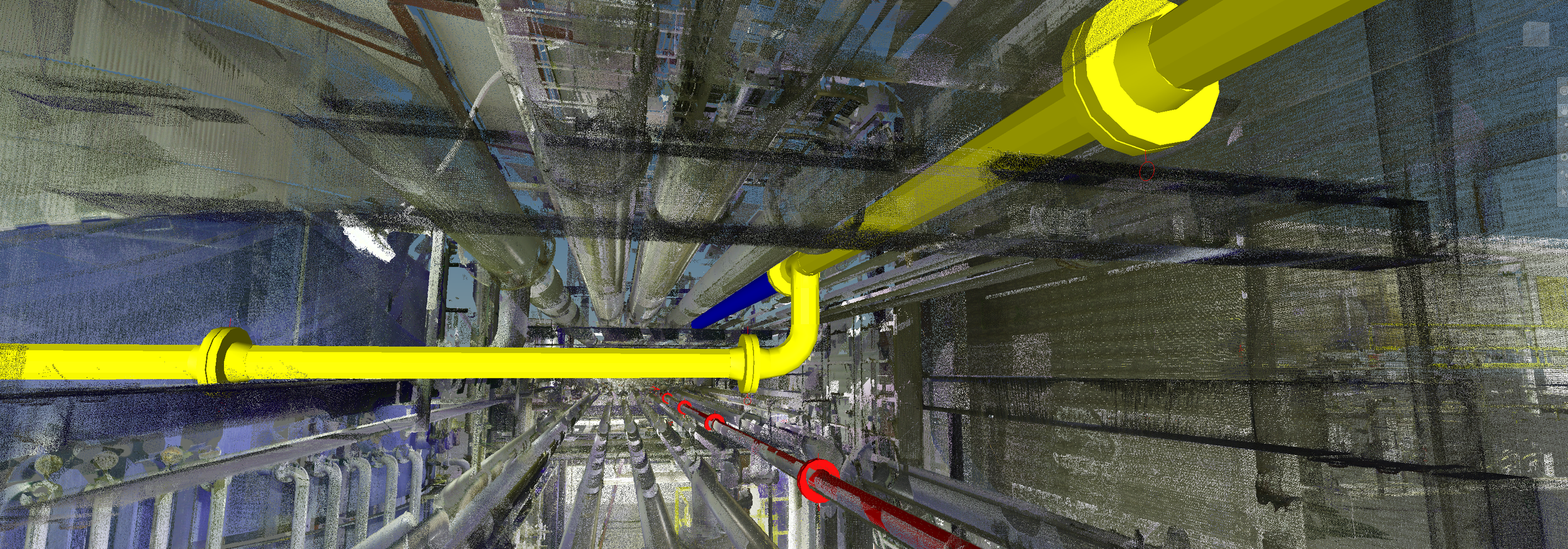 An industrial scene showing a network of pipes in yellow, blue, red, and gray, running vertically and horizontally within a large facility or plant.