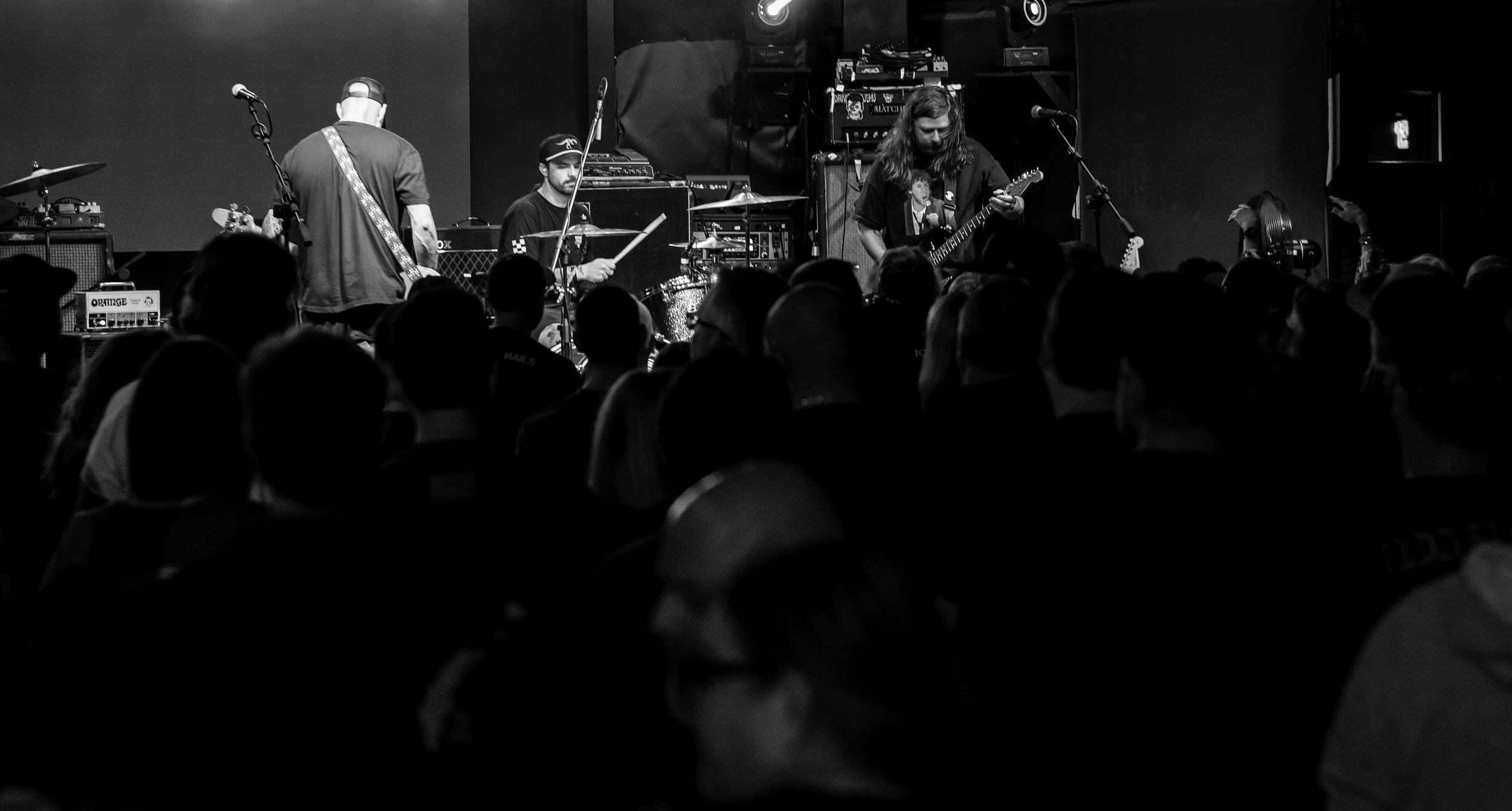 Black and white photo of a band performing on stage with an audience watching.