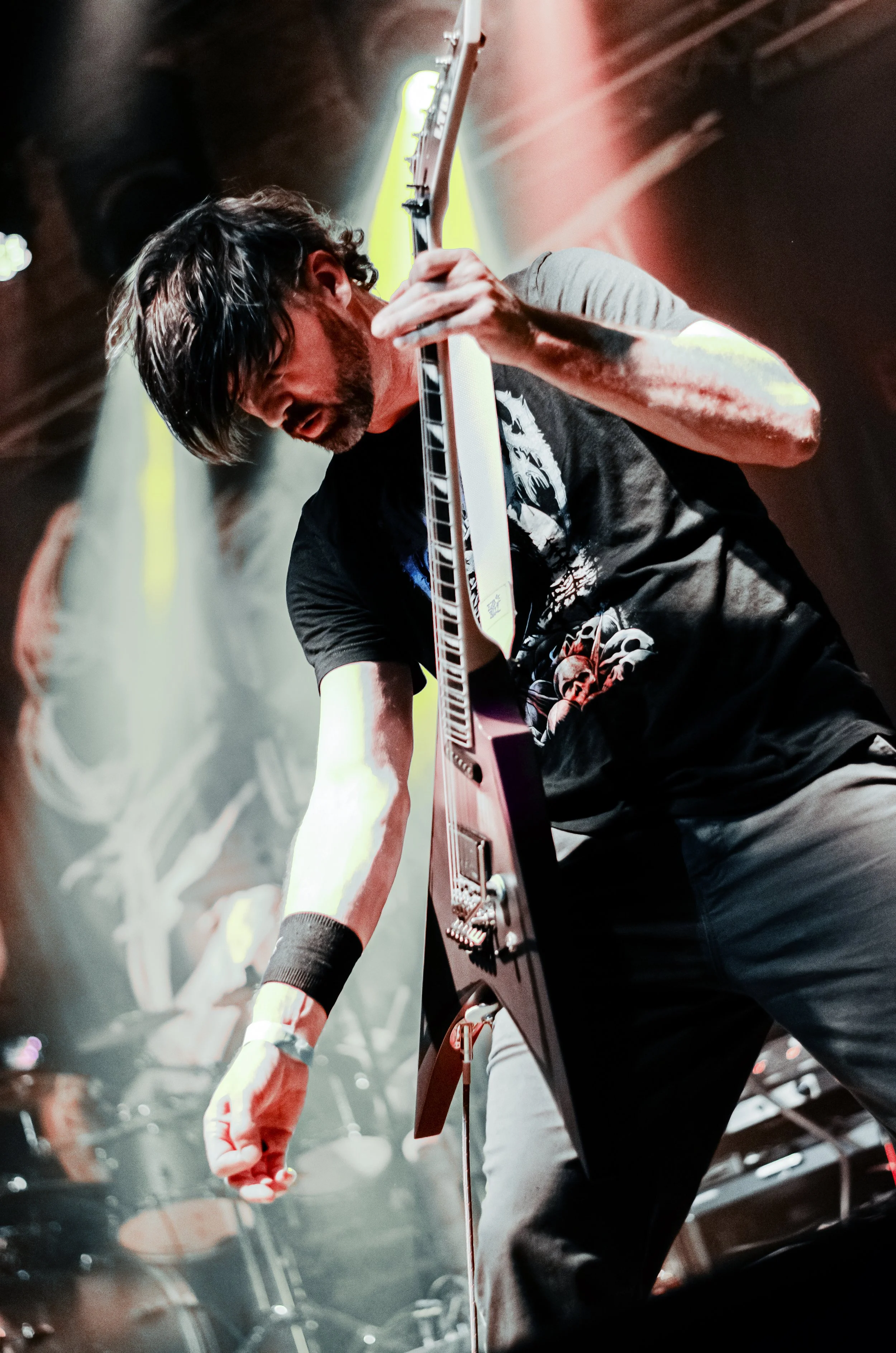 A musician playing a guitar on stage, close-up shot from a low angle, with colorful stage lights and smoke in the background.