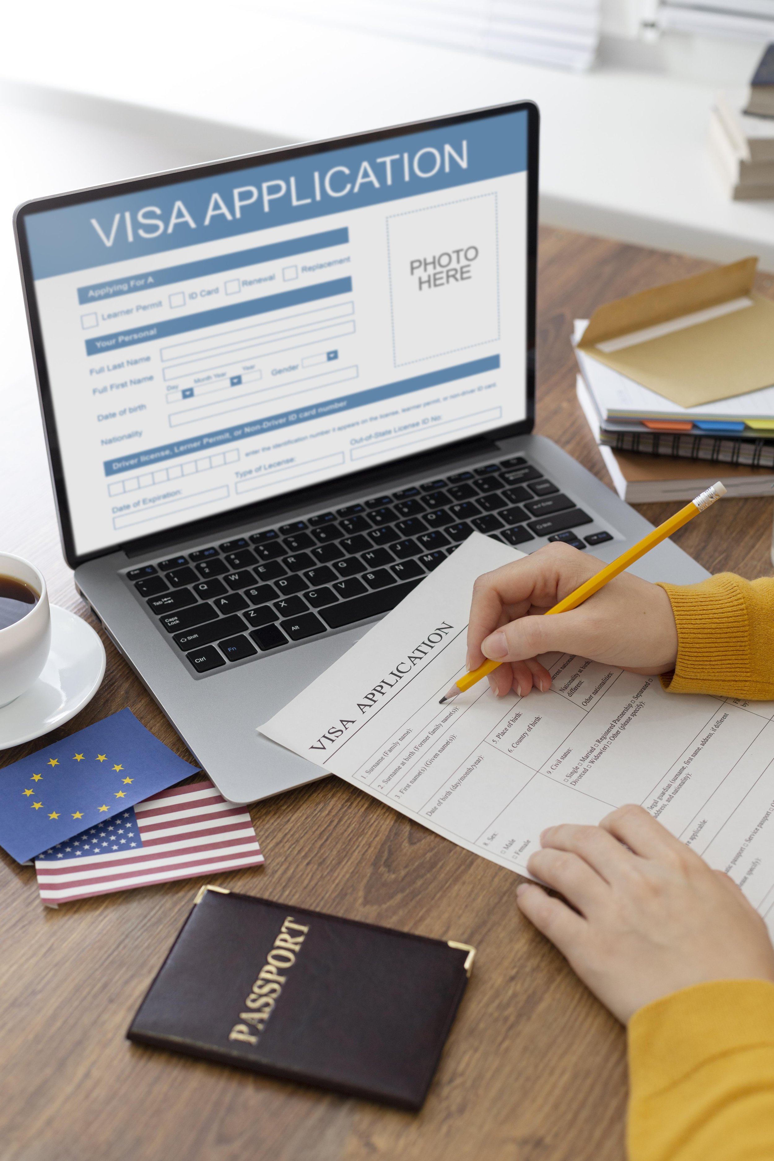 A person filling out a visa application form at a desk, with a laptop displaying the visa application on the screen, a passport, and various flags including the European Union and United States flags.