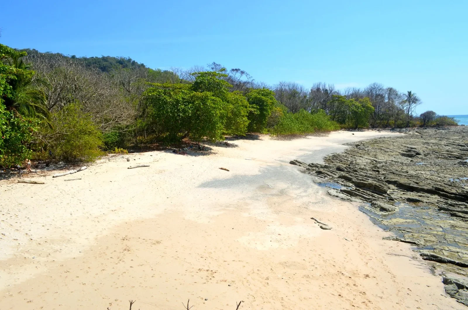Secluded Playa Cuevas (Playa Suecos) beach with white sand and rocky tide pools in Mal País, Costa Rica