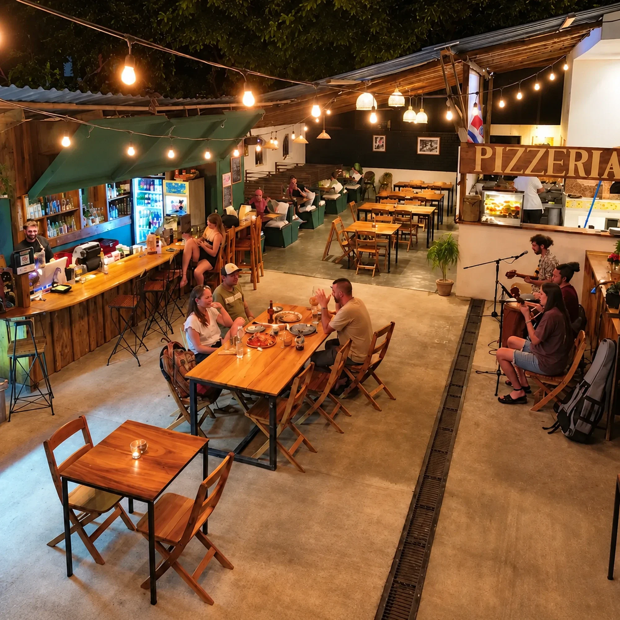 Diners and musicians at Delizie Italian Restaurant & Pizzeria in Mal País, Costa Rica, beneath warm string lights.