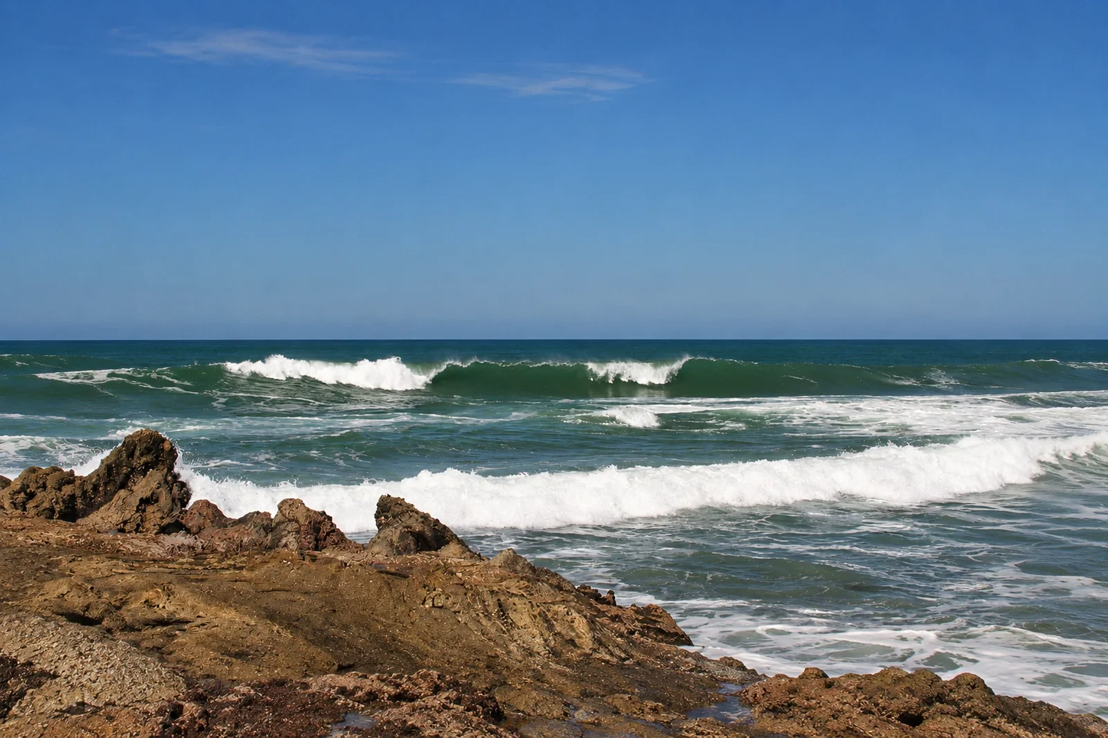 Waves breaking off the rocky shoreline at Mar Azul surf spot in Mal País, Costa Rica.