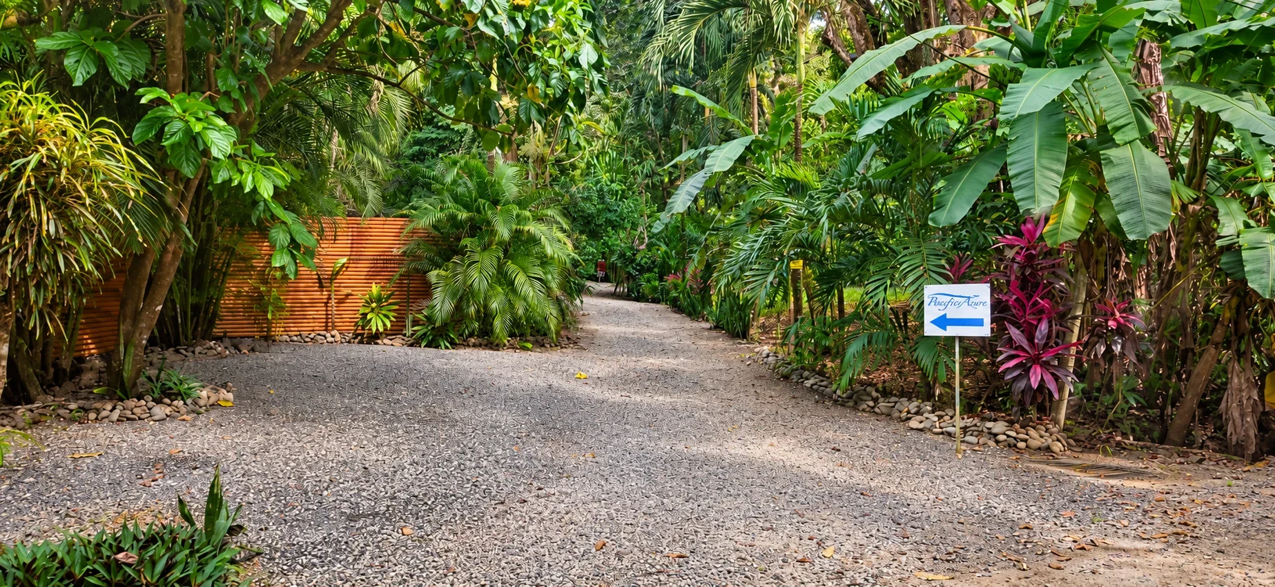 White Pacific Azure sign with a blue arrow pointing left at the driveway surrounded by tropical plants in Mal País, Costa Rica.