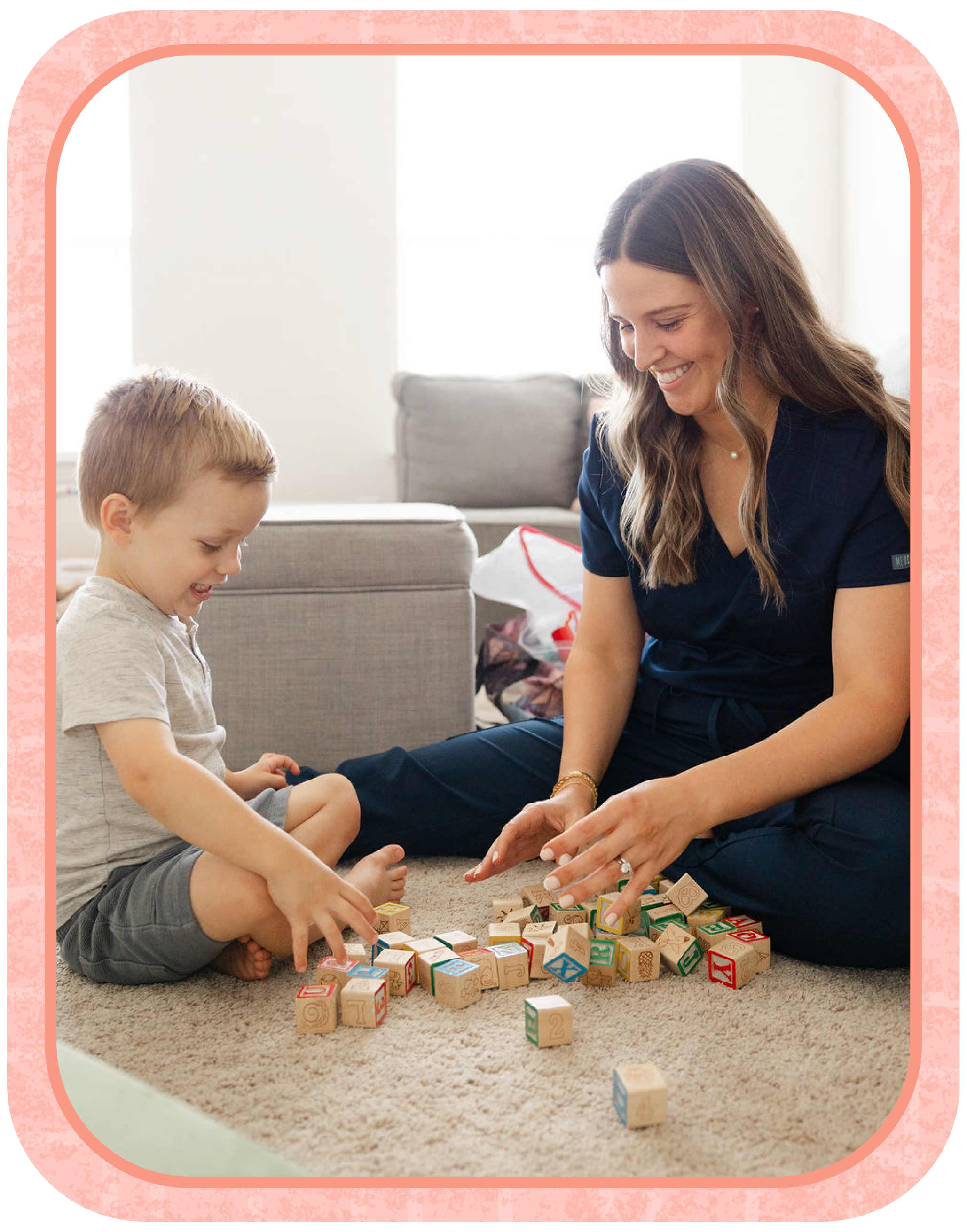 A woman and a young boy sitting on a beige carpet playing with alphabet blocks.