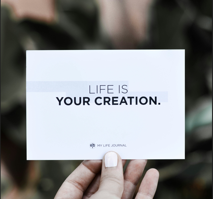 Hand holding paper saying life is your creation