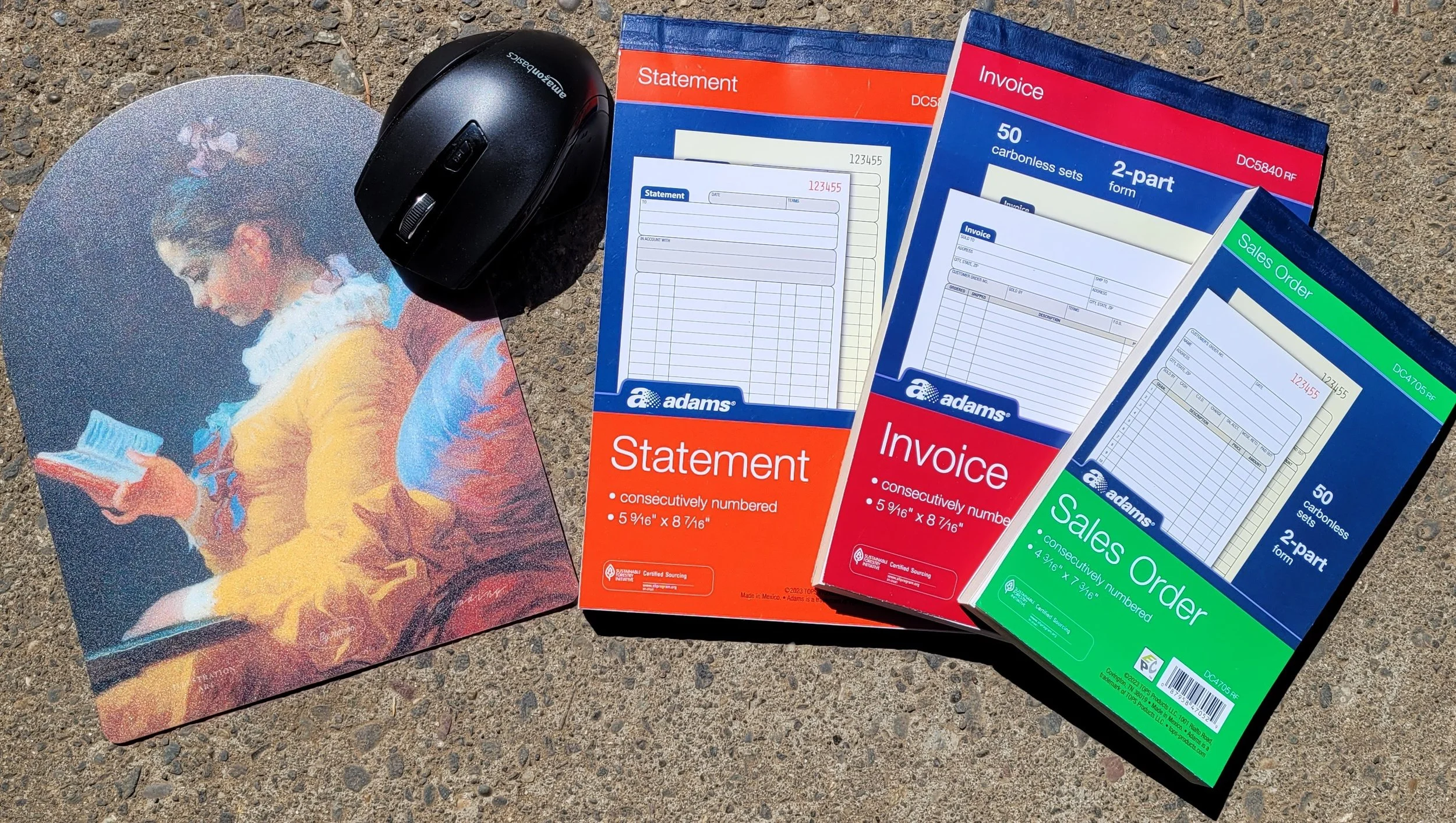 A colorful art print of a woman with short hair reading a book, lying on a textured surface. Next to it are a computer mouse and four packs of office supplies, including statement, invoice, and sales order forms, all labeled with the brand Adams.