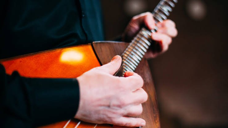 Nahaufnahme einer Person, die auf einer Balalaika spielt.