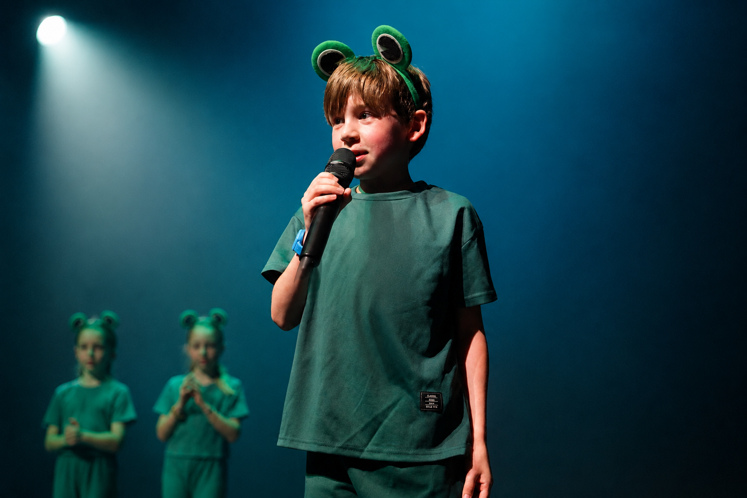 Boy singing into a microphone on stage, performing for a LAMDA musical theatre exam