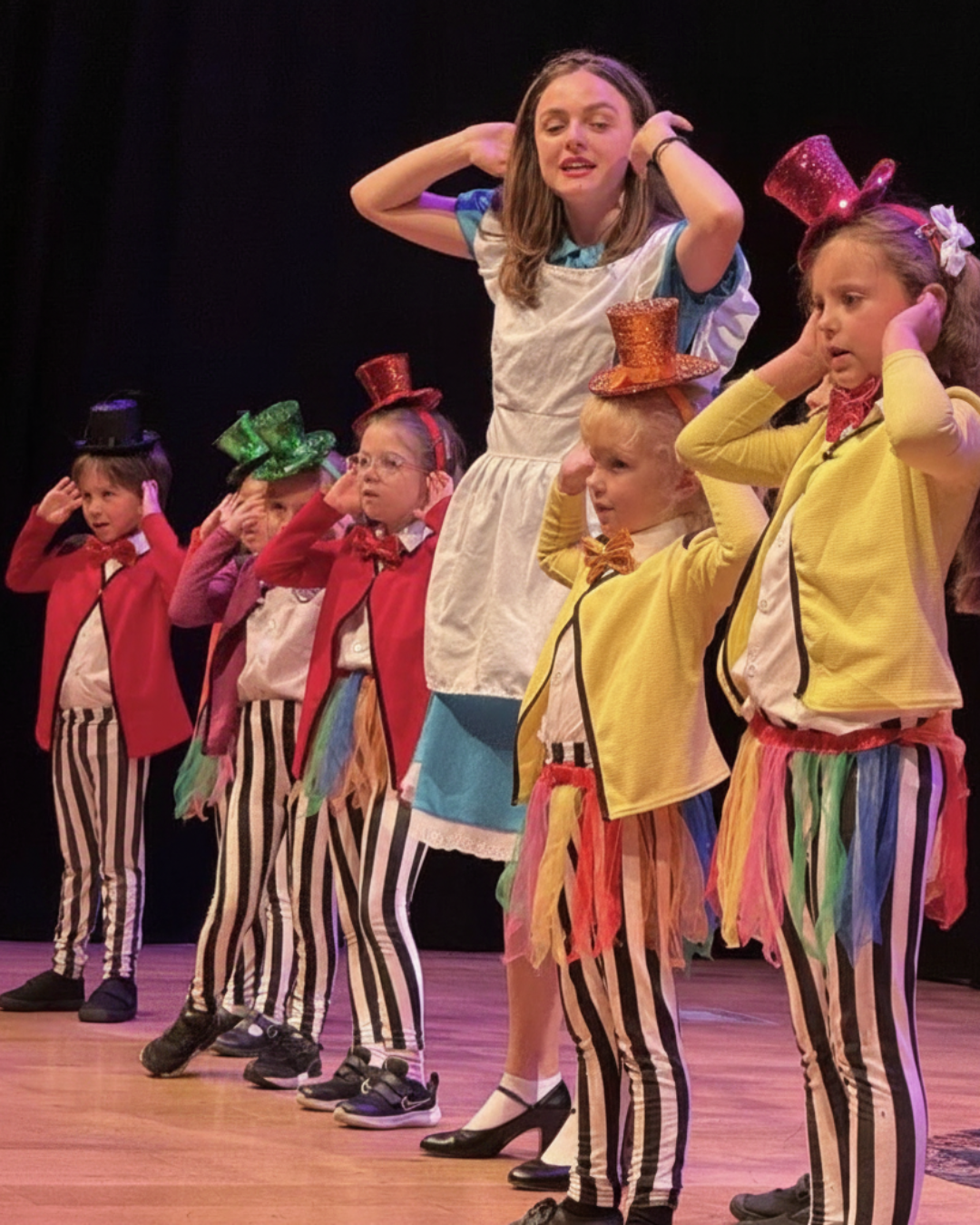 Children in colourful costumes performing in an Act One Rising Stars musical theatre show for ages 5–6