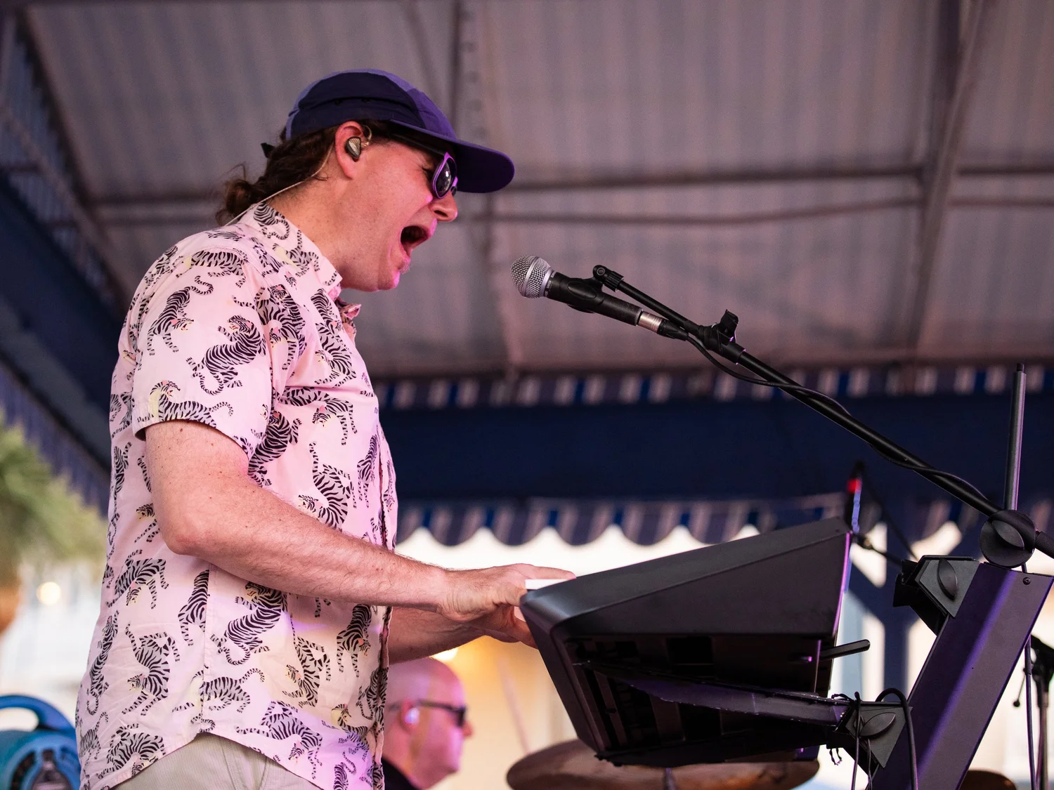 Female vocalist singing and playing keyboard at an outdoor concert.