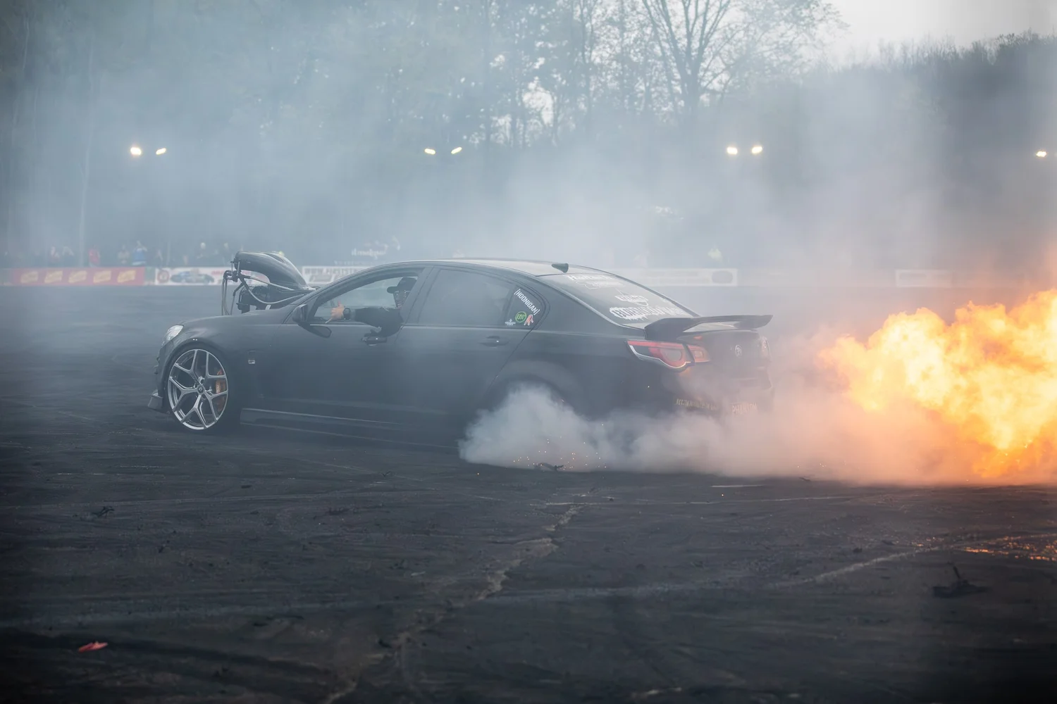 Black sports car producing flames and tire smoke during a burnout at Big Indian Drift Pit.