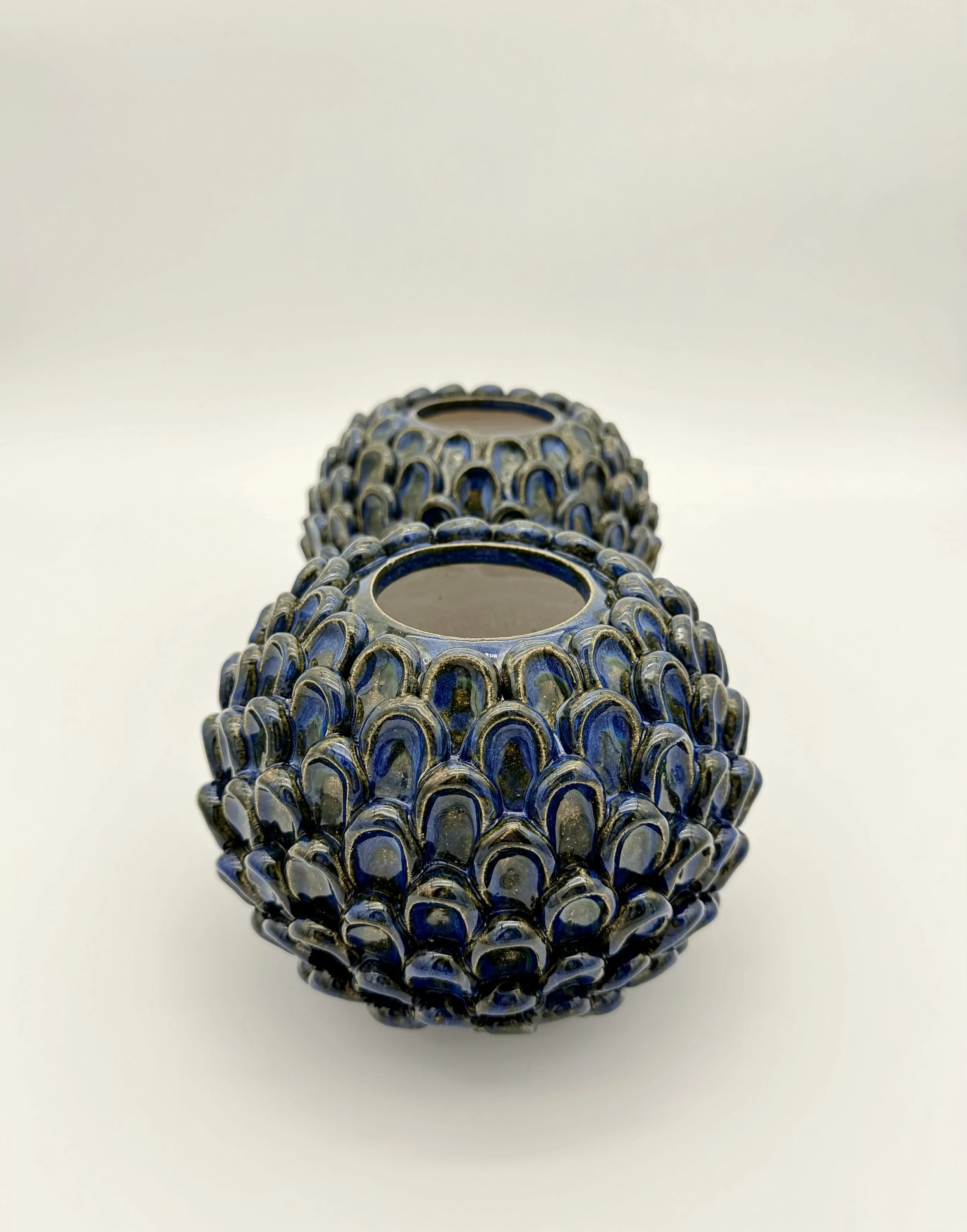 Three decorative vessels with rounded, textured surfaces, arranged in a line against a plain white background.