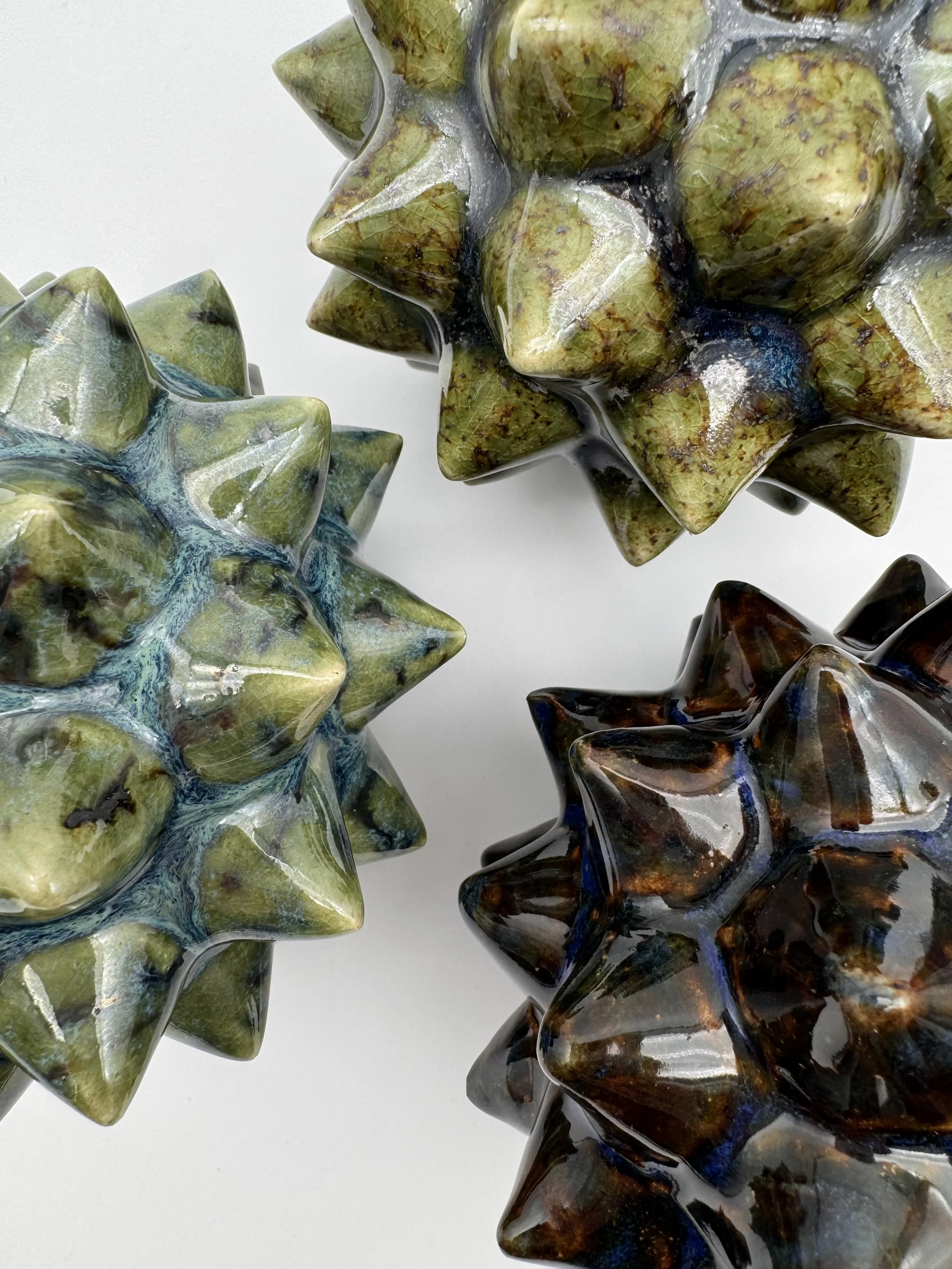 Close-up of four handcrafted glass starfish sculptures with different colors and textures on a white background.
