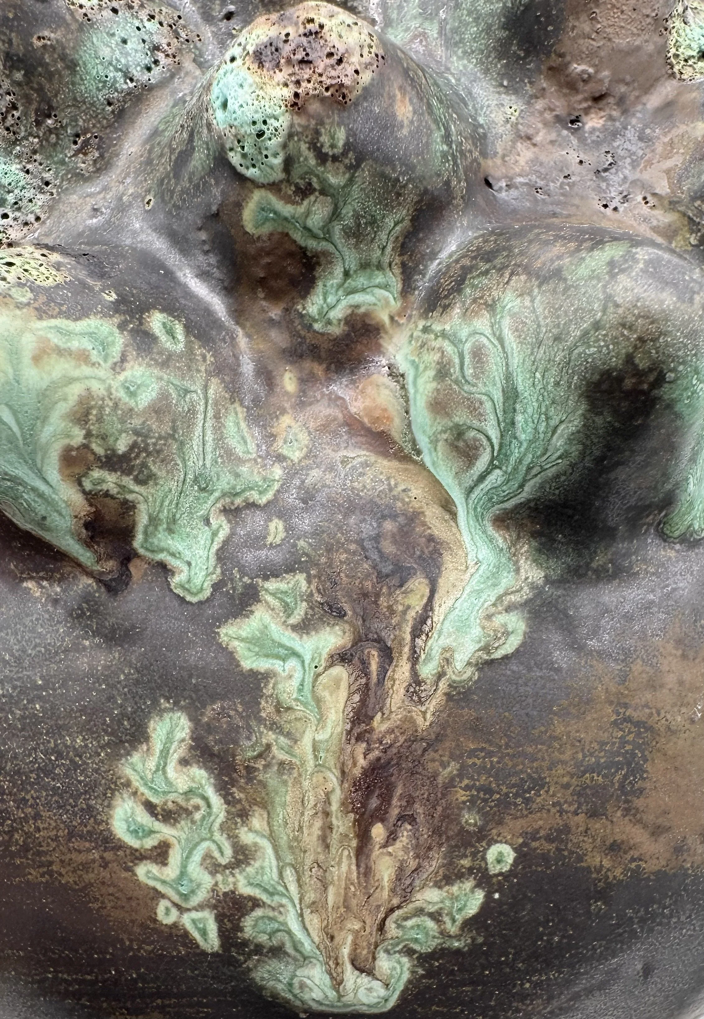 Close-up of a metallic surface with green patina and swirling patterns.