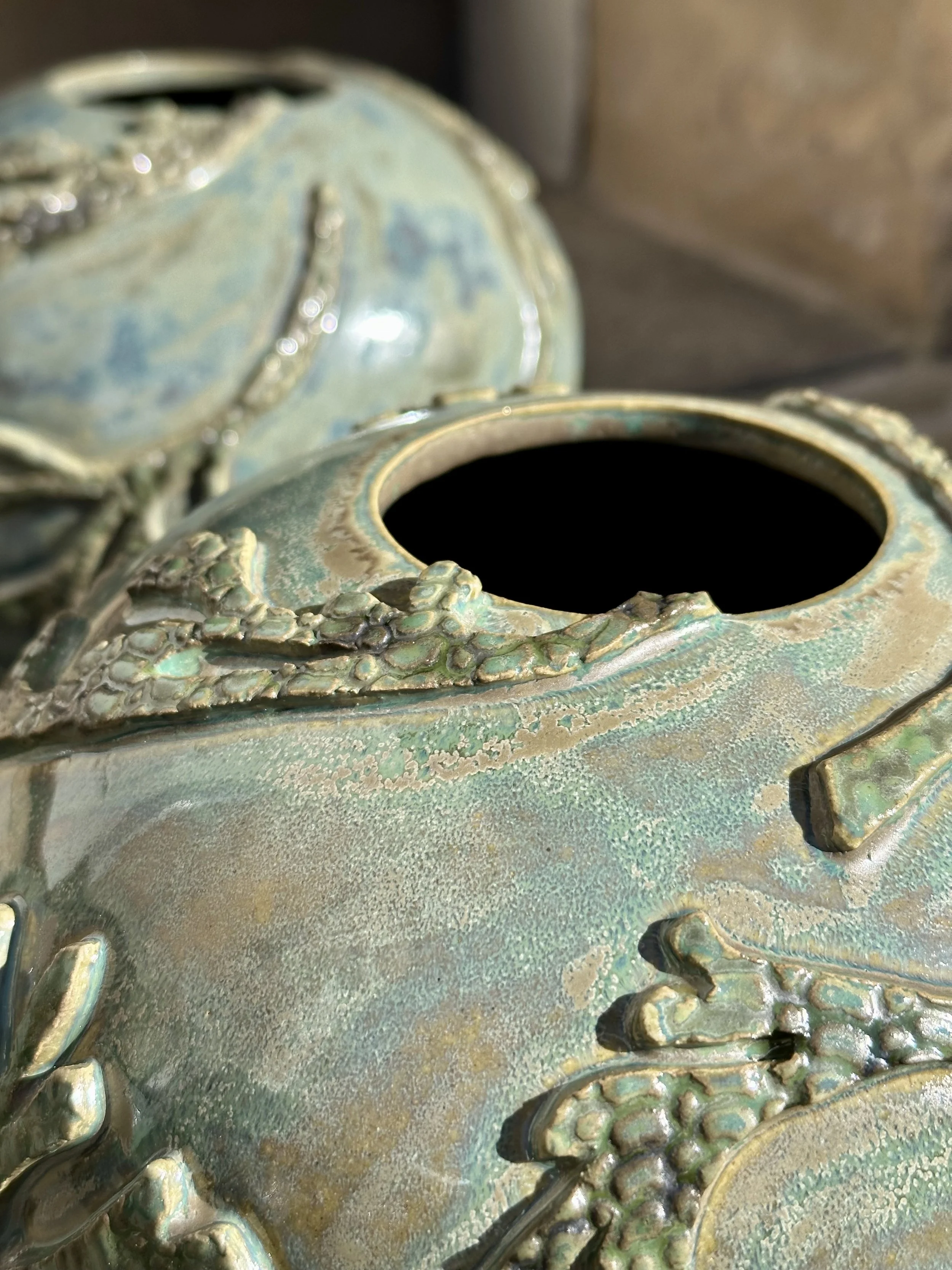 Close-up of a decorative, metallic lantern with dragon-shaped embellishments in a greenish patina finish.