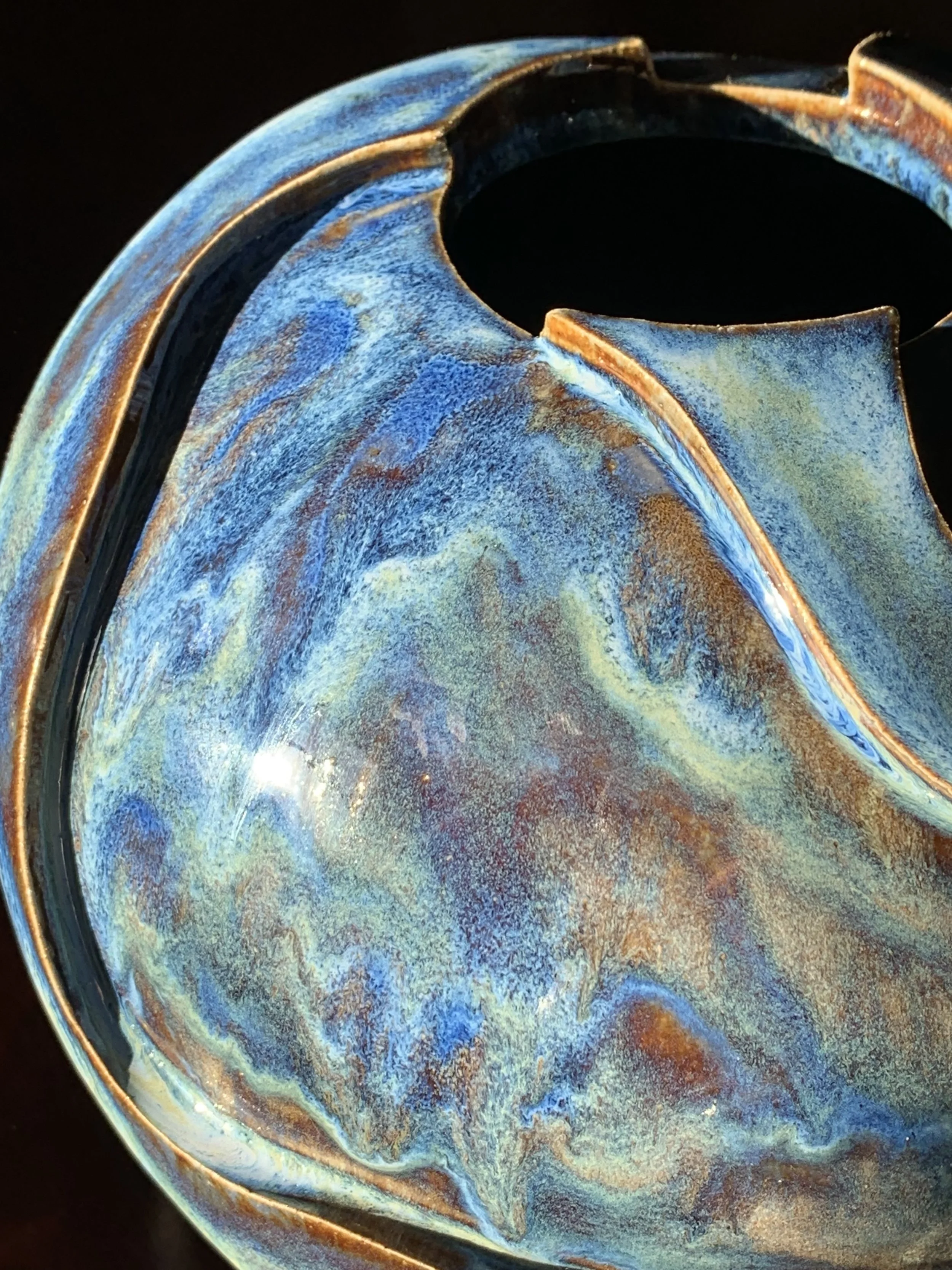 Close-up of a melting ice cream cone with a swirl of blue, yellow, and brown colors.